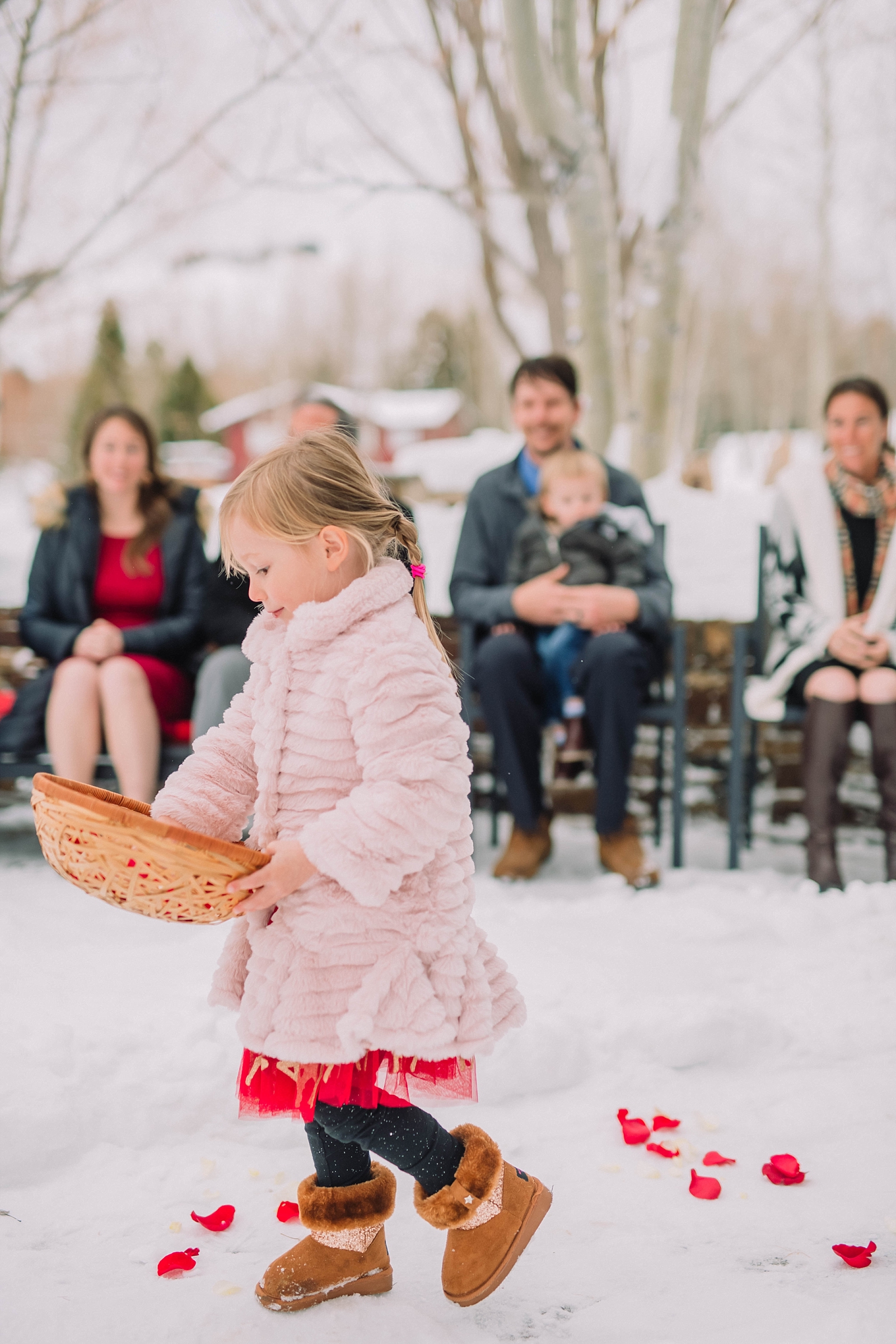 little girl walking down aisle in warm clothes during winter wedding