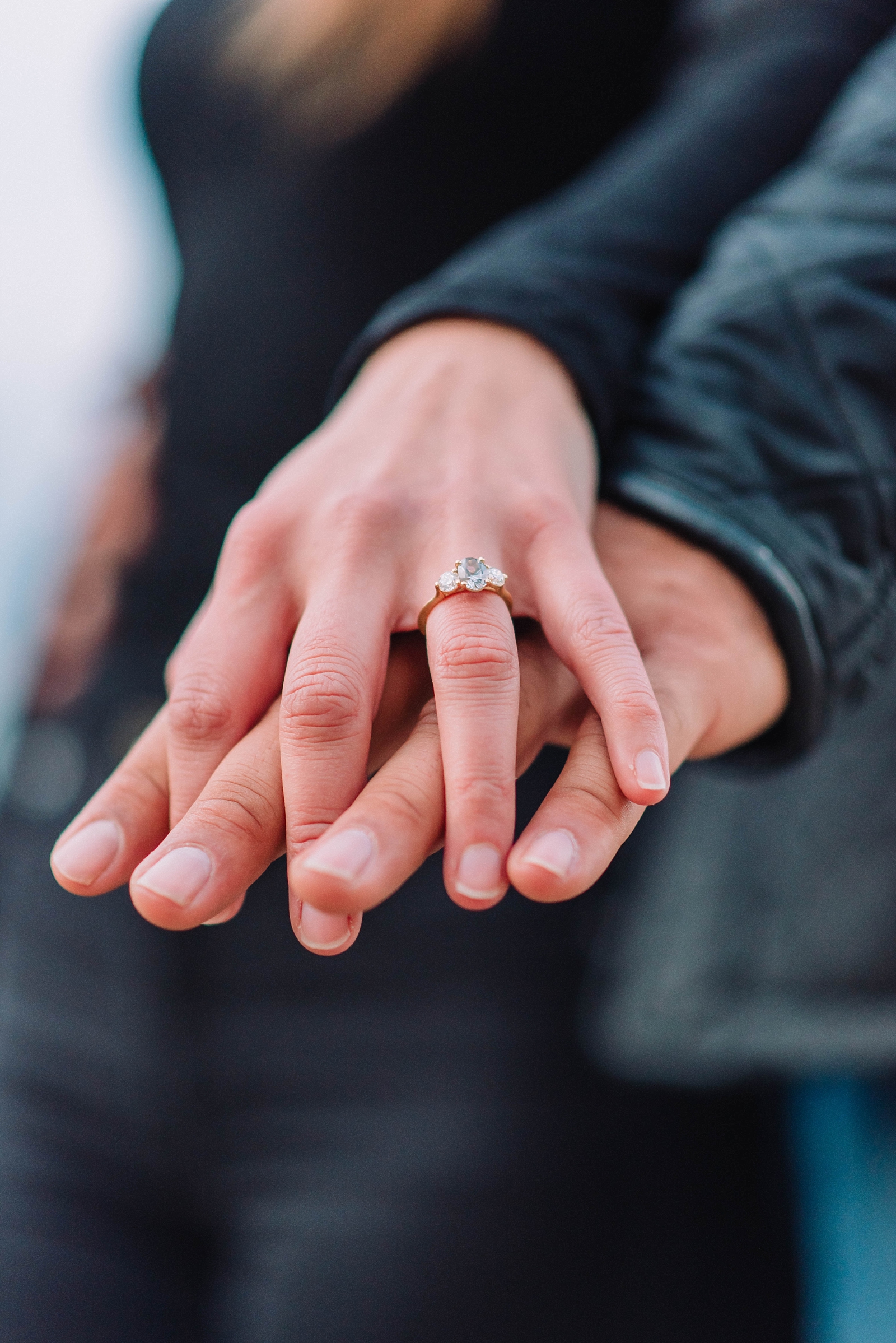 engaged woman's hand on partners hand showing off ring