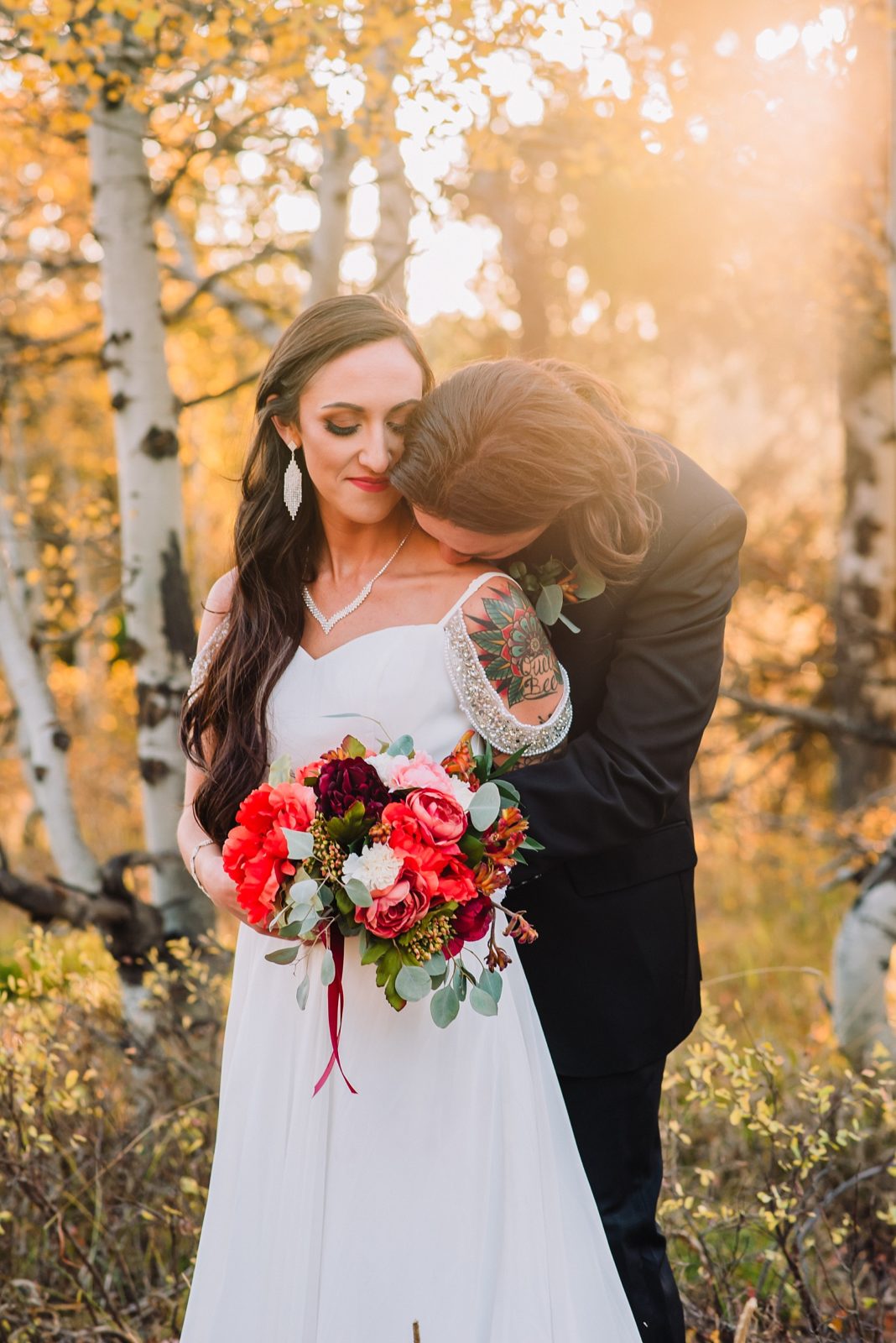 groom kissing bride's neck during fall outdoor wedding