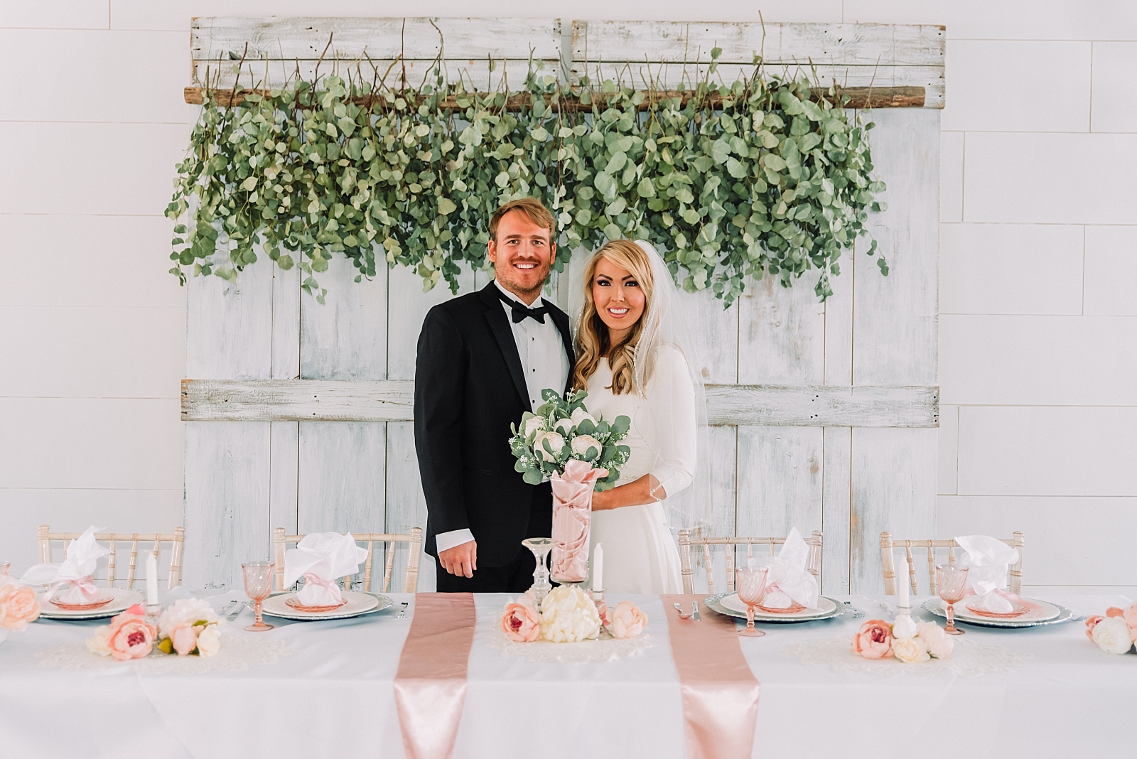 bride and groom portraits in front of floral backdrop wall