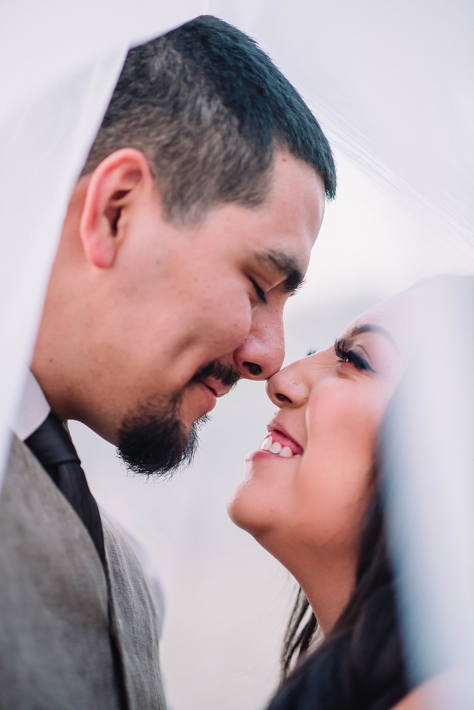 bride and groom touching noses and smiling under bride's veil at Salt Lake Valley wedding