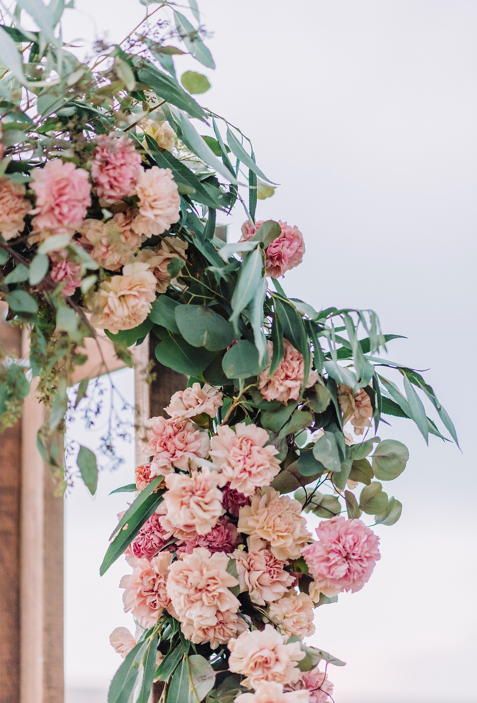 pink and coral wedding flowers on an arch for the ceremony