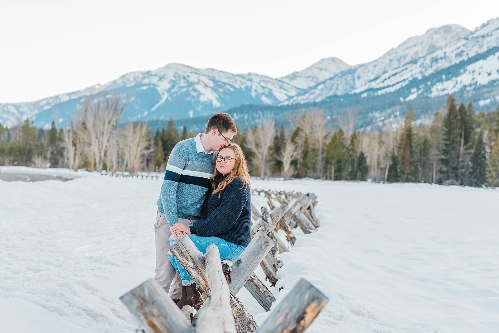 young recently engaged couple wearing winter engagement outfits during their spring engagements at taggart lake during their snowy session