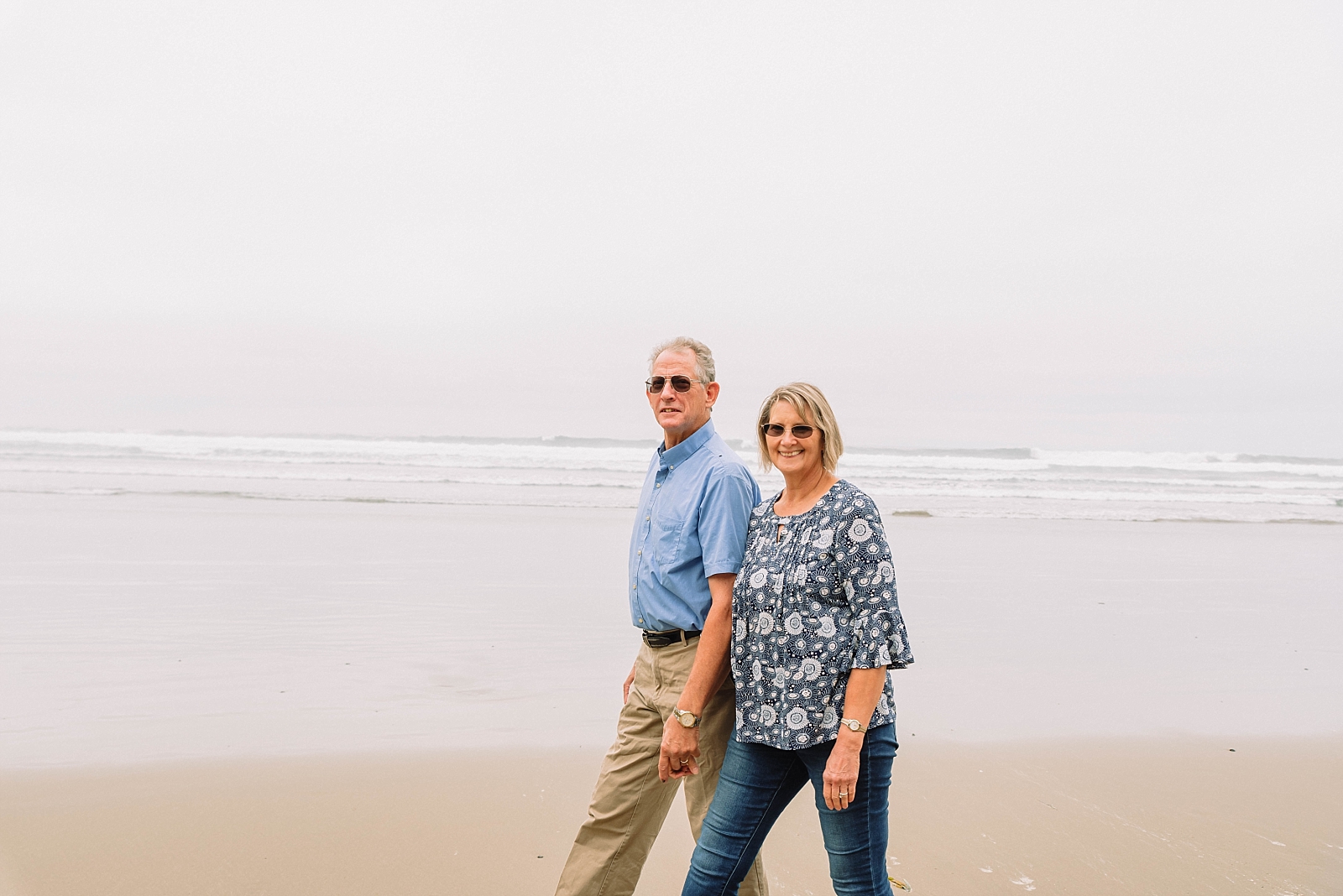 couple walks on the beach while holding hands at the oregon coast