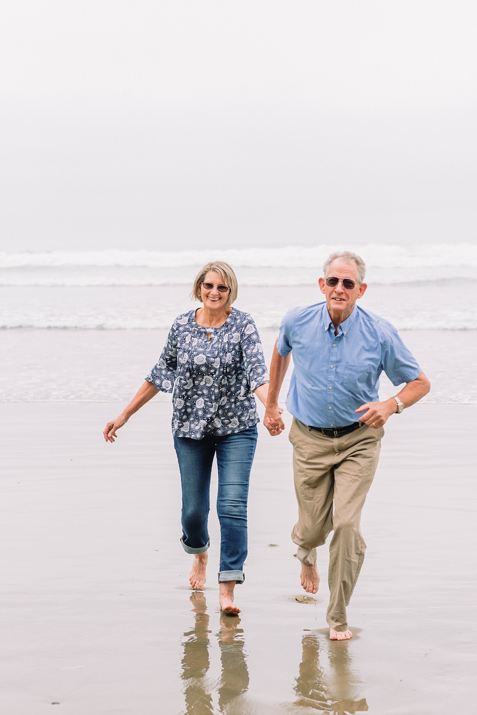 older couple runs on the beach together during anniversary session