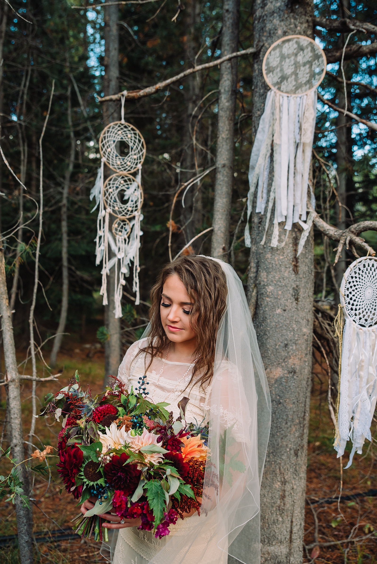 earhty fall elopement in Island park with boho wedding decor in the woods, bride holding an warm bouquet of fall flowers