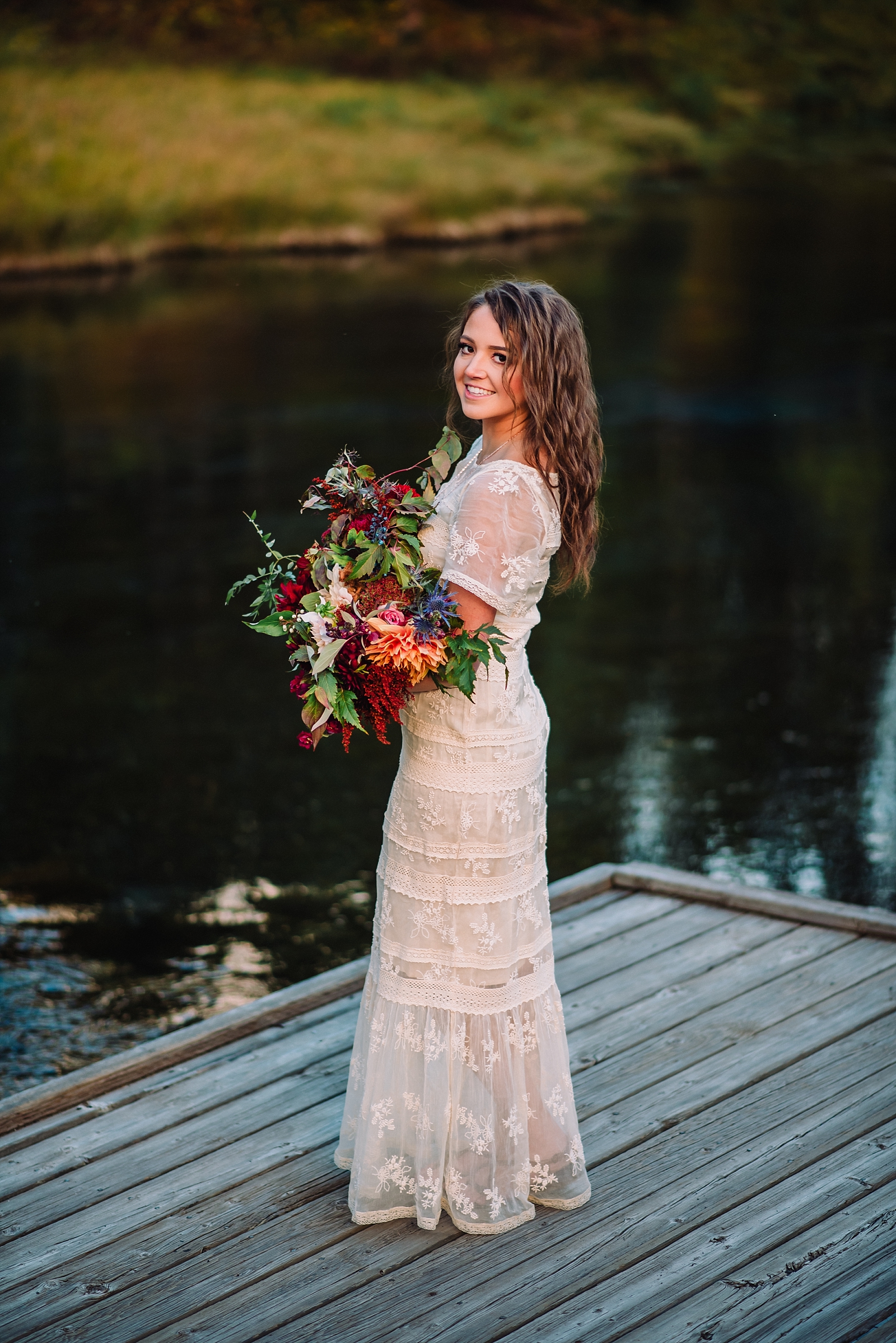 bride standing on a dock at Island Park while holding her bouquet and looking over her shoulder at the camera