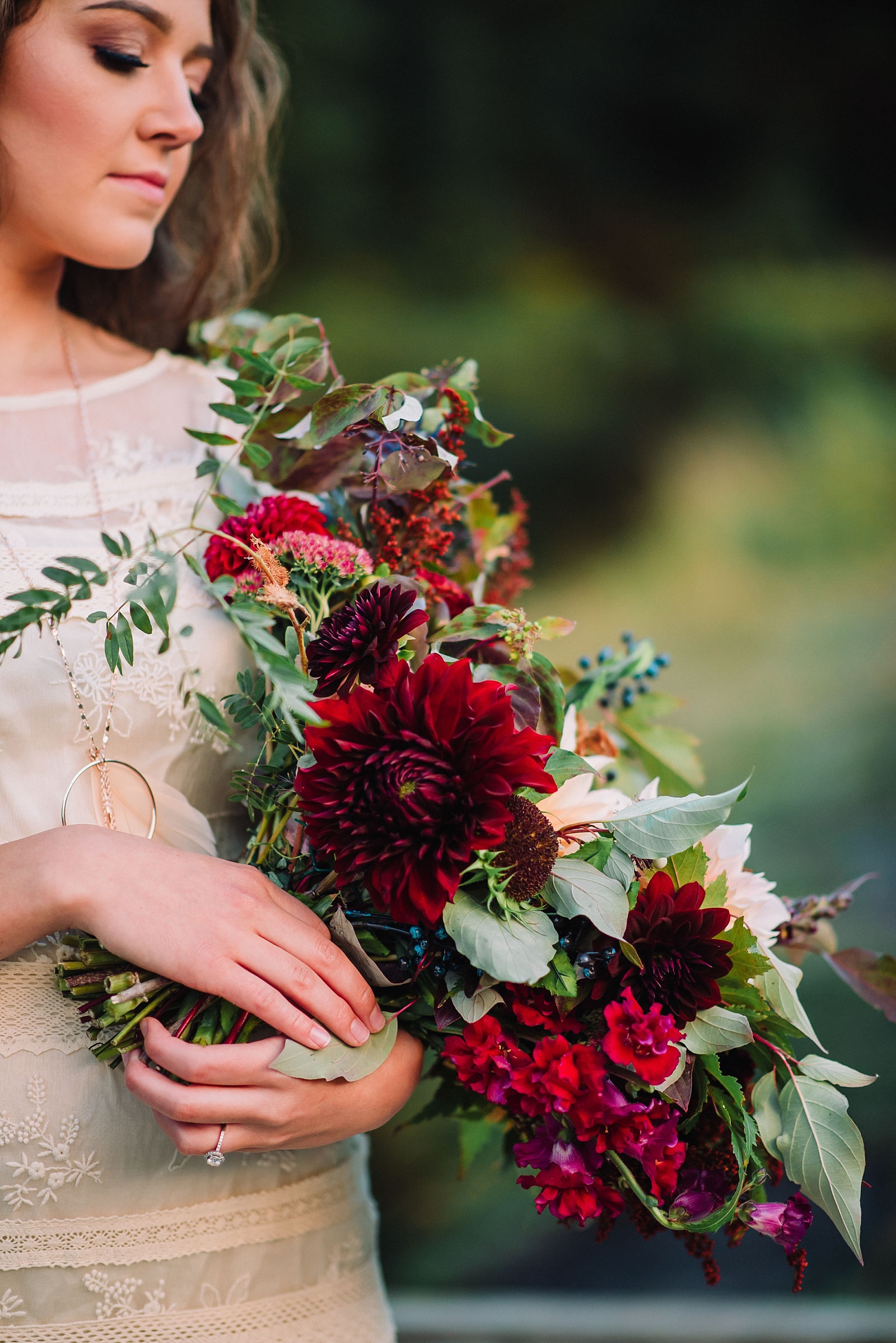 warm fall bouquet for a boho idaho wedding with bride holding the bouquet and looking down at it