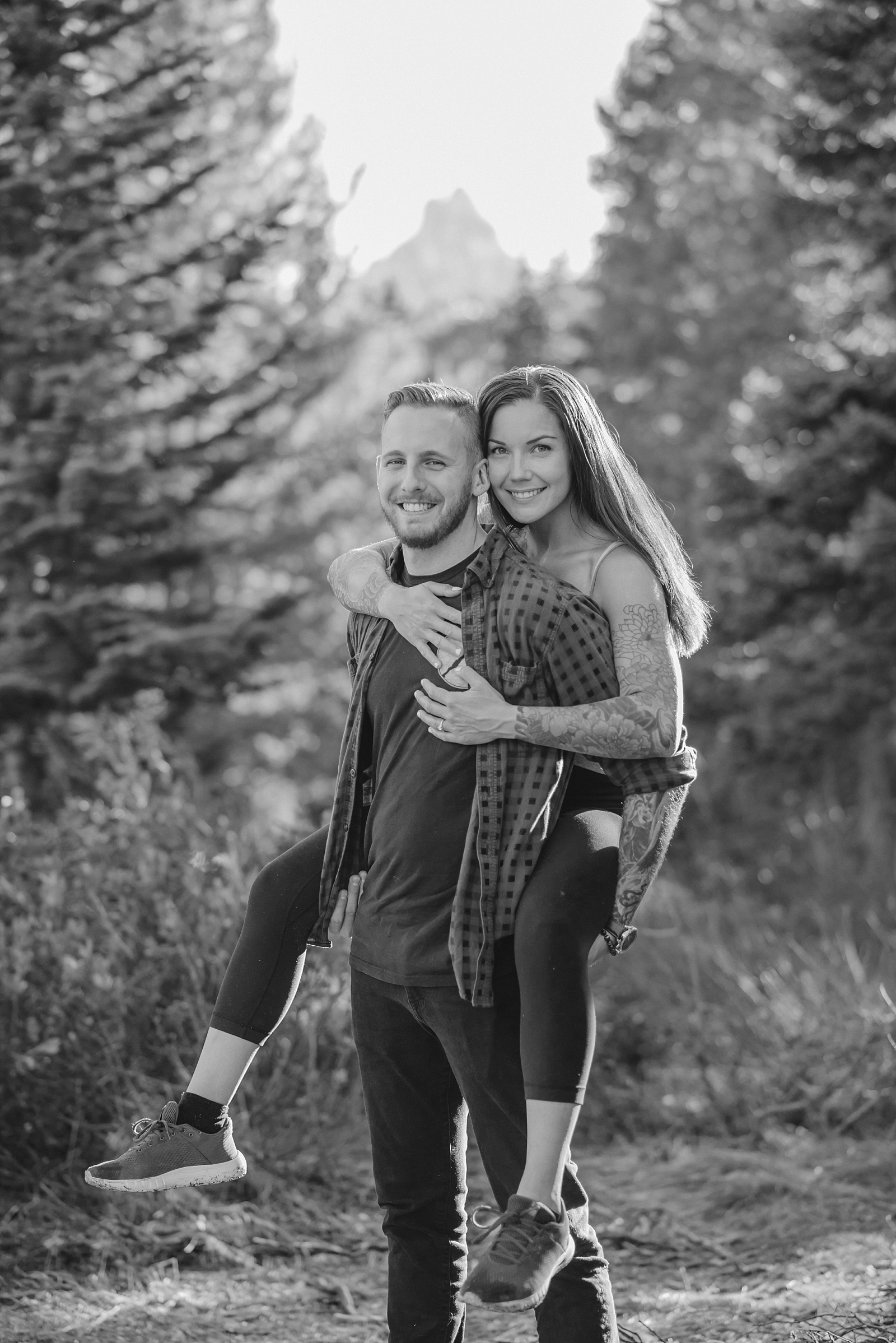 man gives woman a piggy back ride in engagement photos