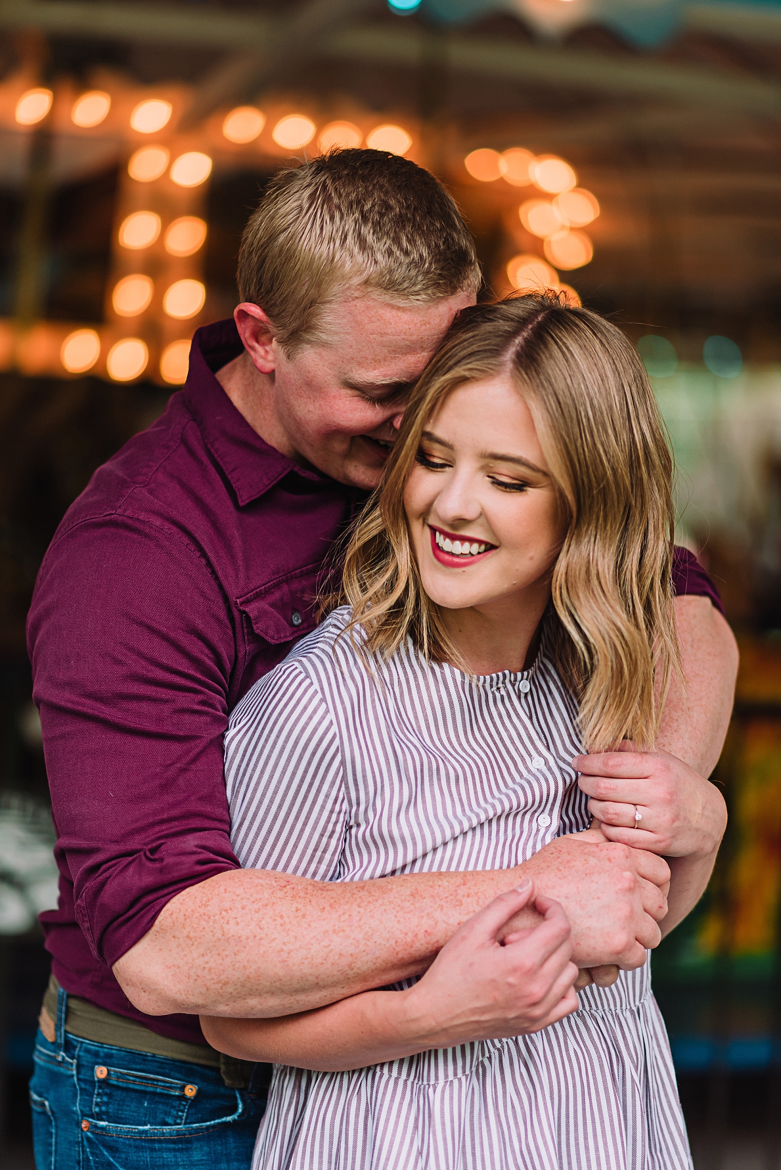 young man and woman hugging and laughing together at rexburg carousel