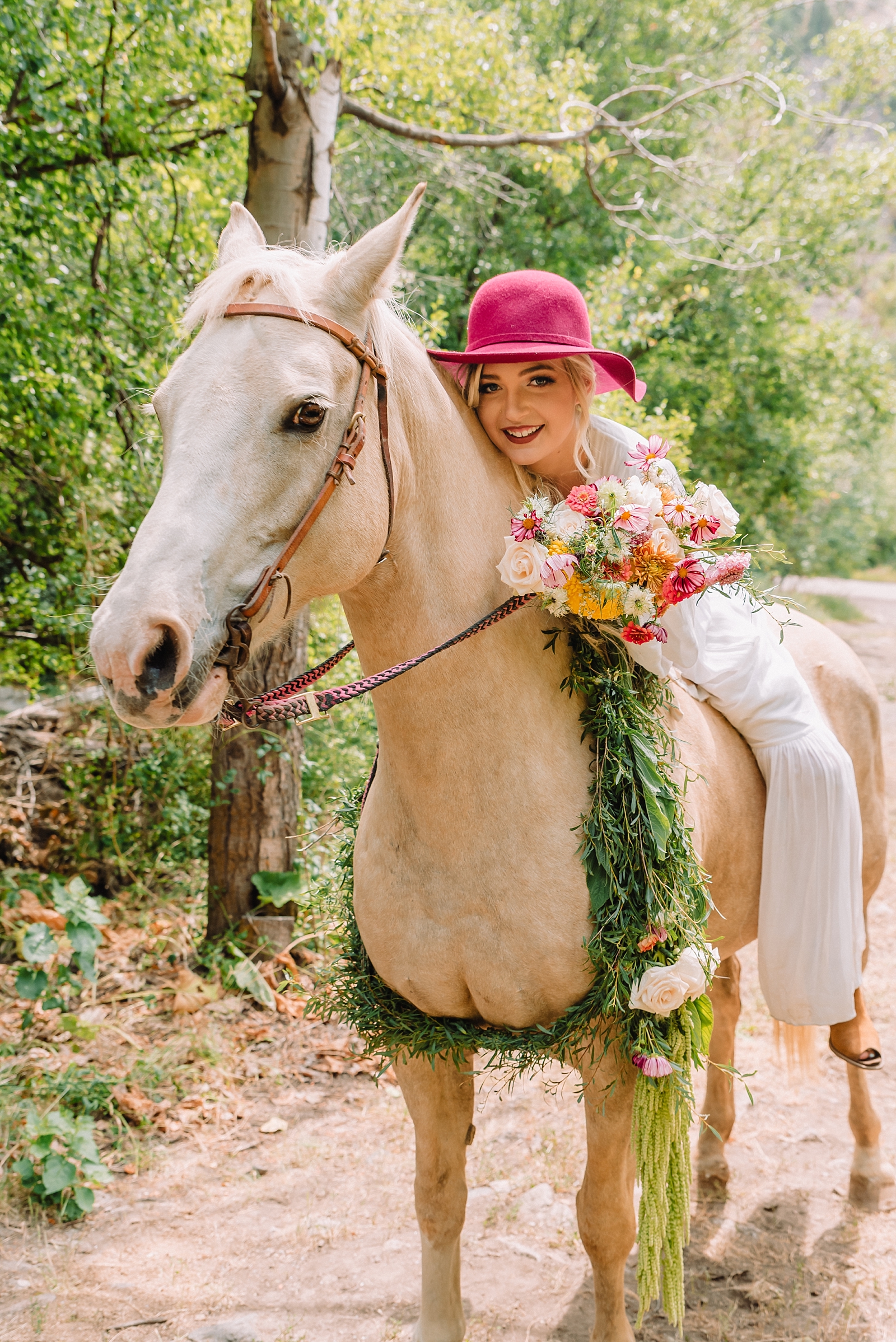 woman sitting on horse wearing pink hat and holding bouquet