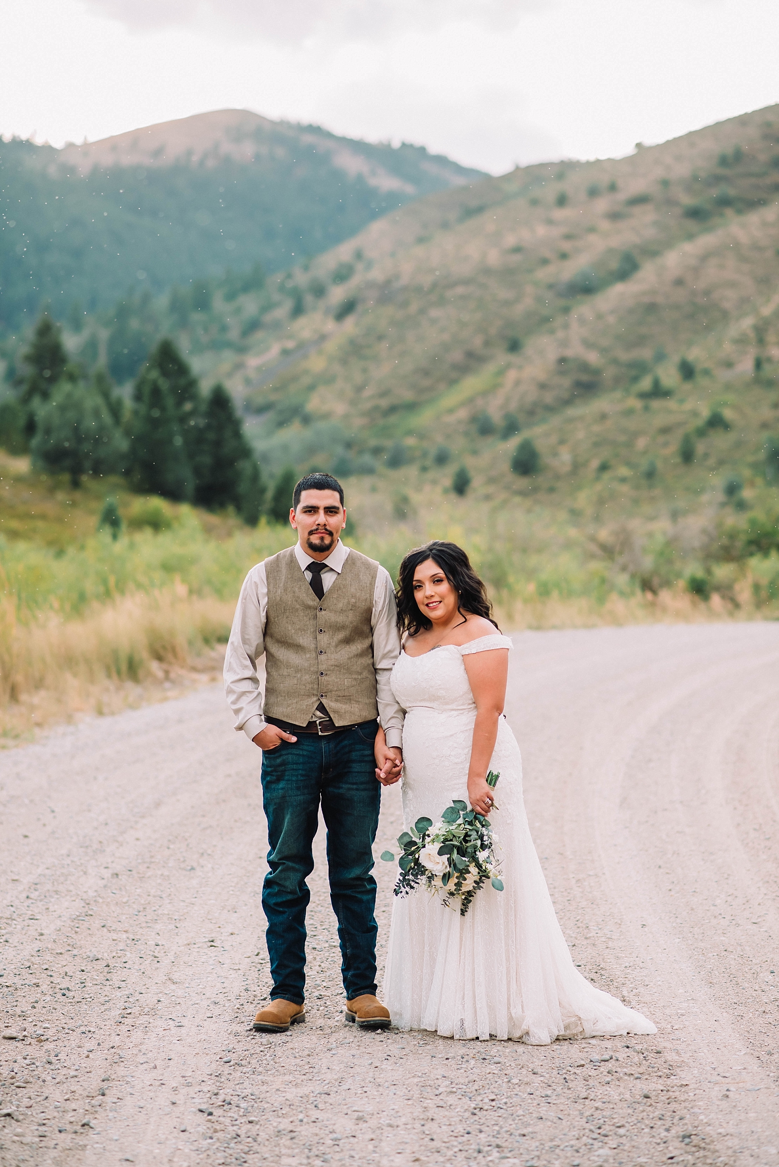 bride and groom hold hands as they stand on a dirt path in the Grand Tetons with mountains behind them