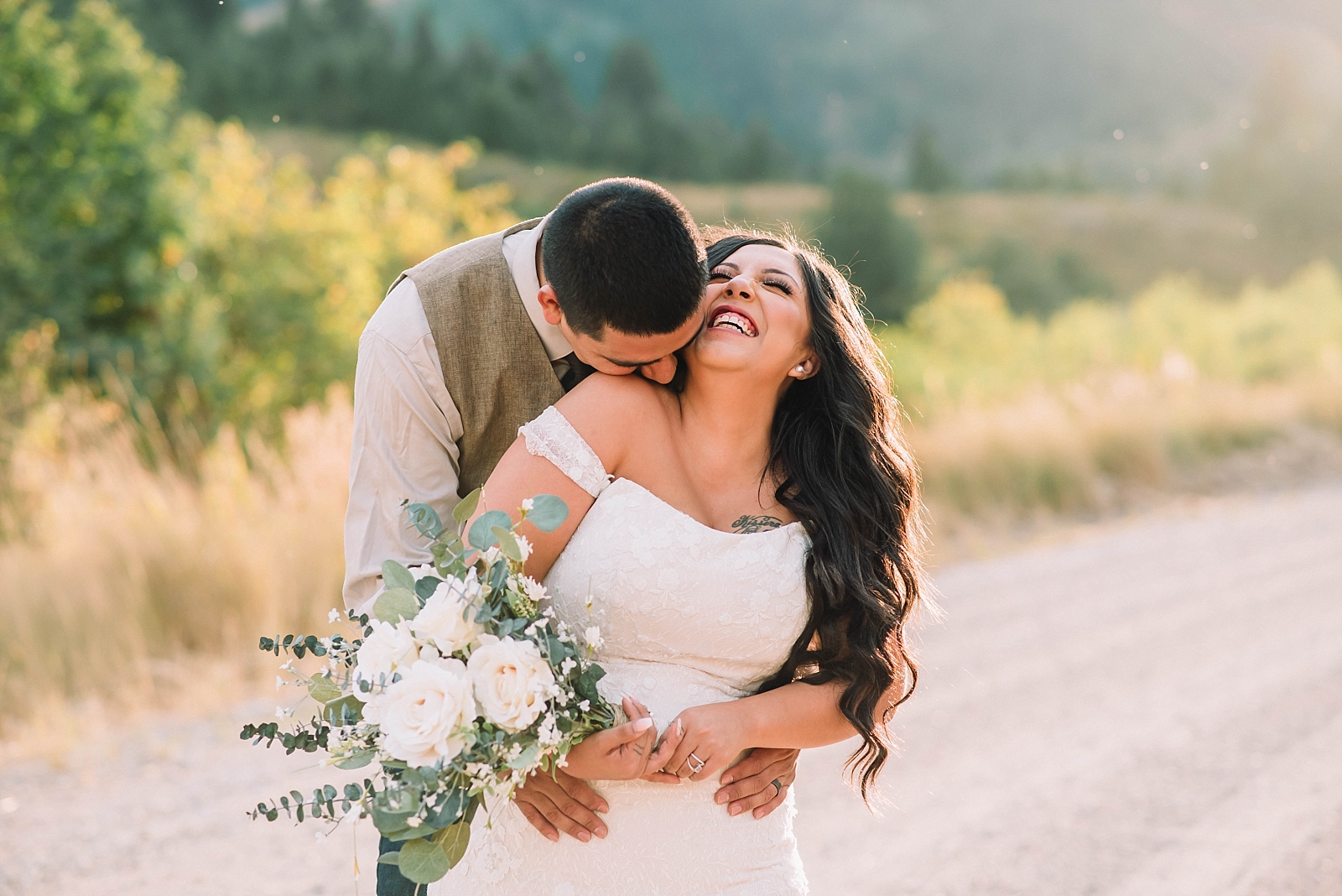 bride laughing as her groom kisses her shoulder int he Grand Tetons for their summer wedding 