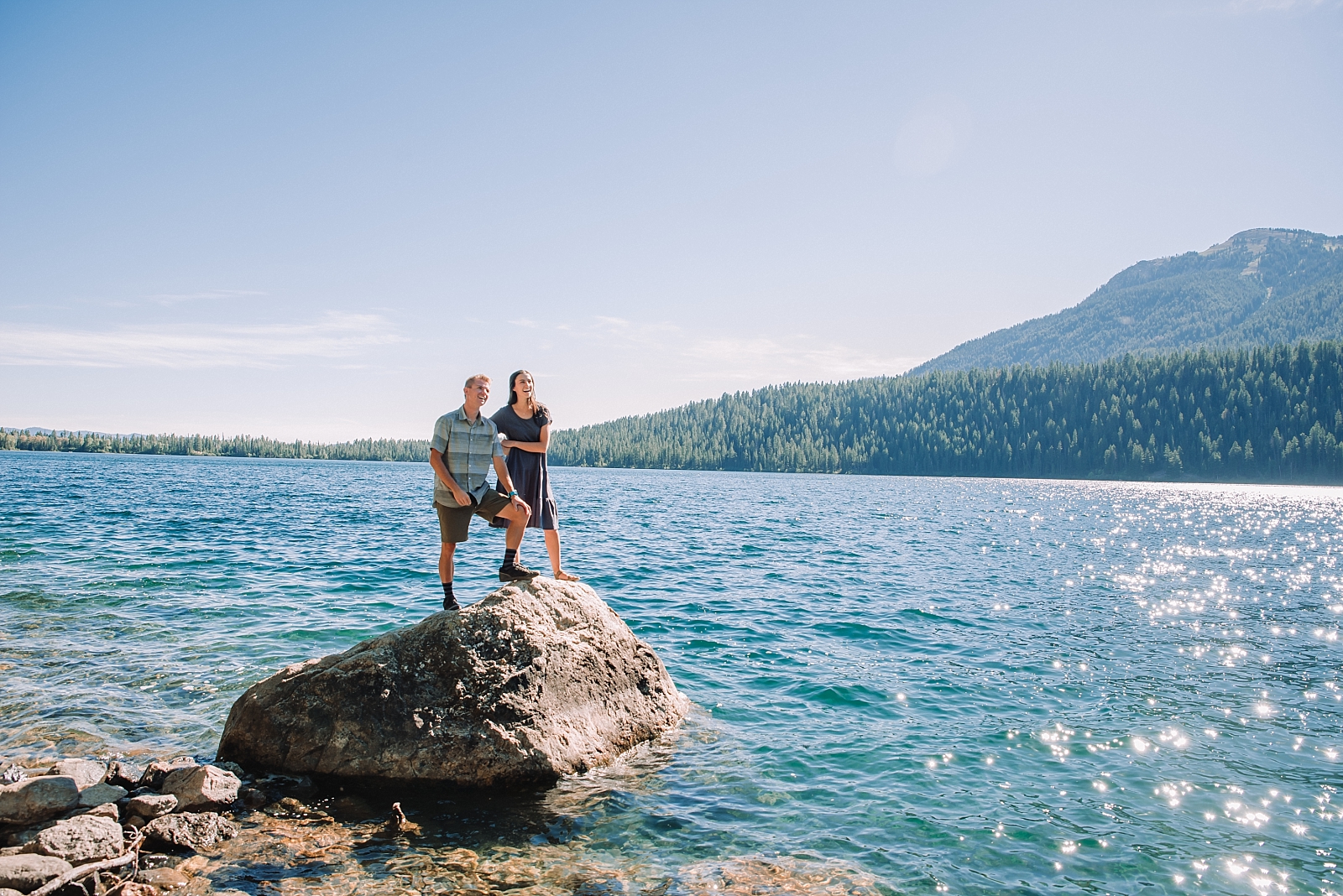 couple standing on rock in the middle of water at tetons