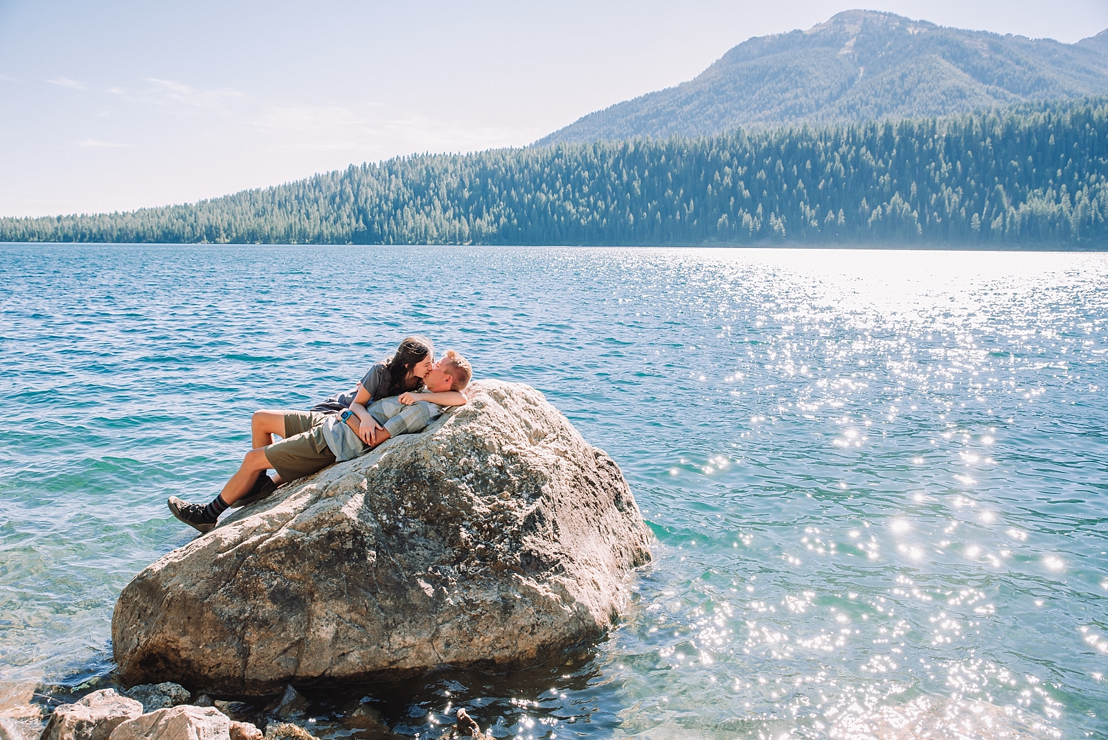 man and woman laying on boulder at phelps lake in Jackson Hole