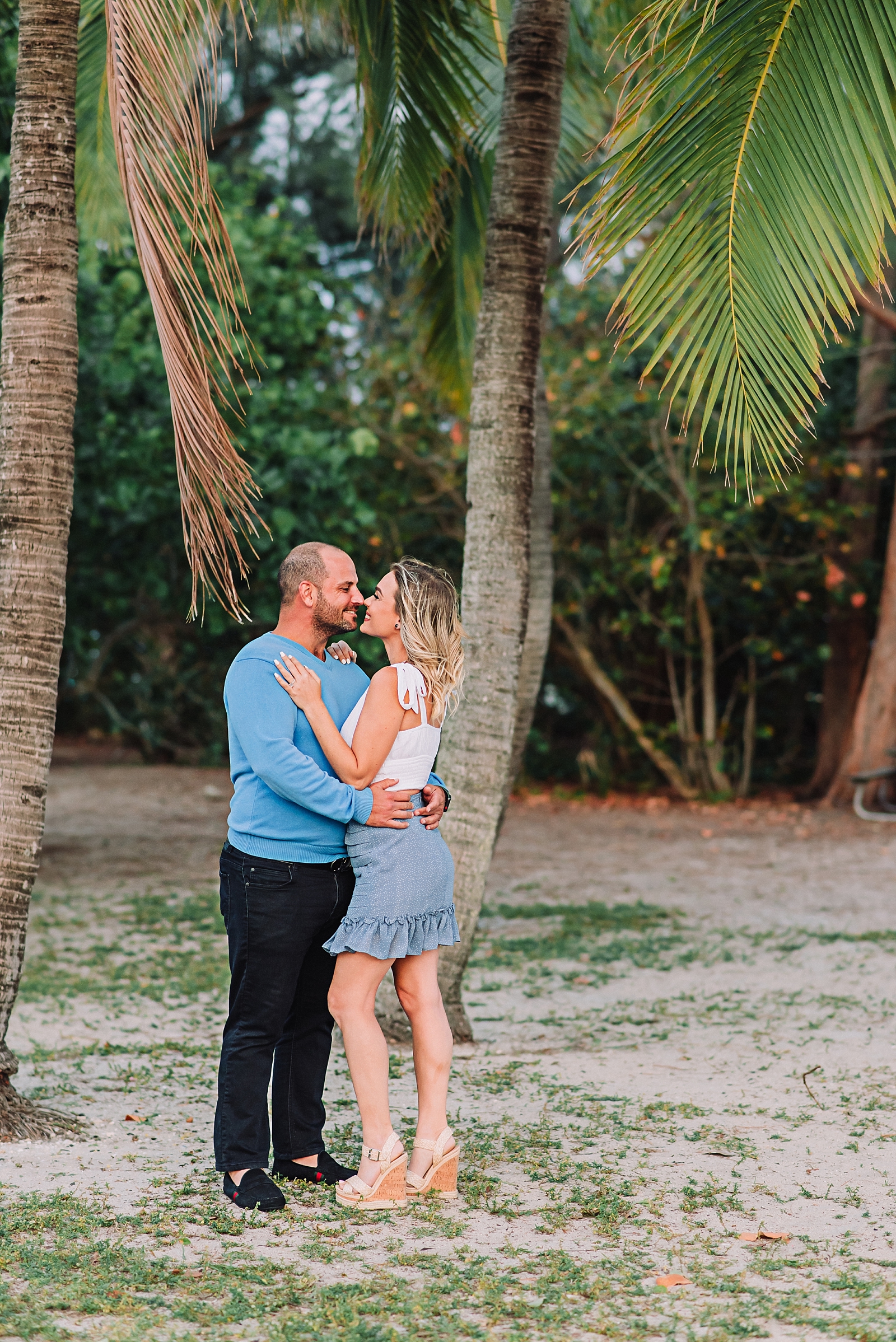 couple snuggles under a palm tree