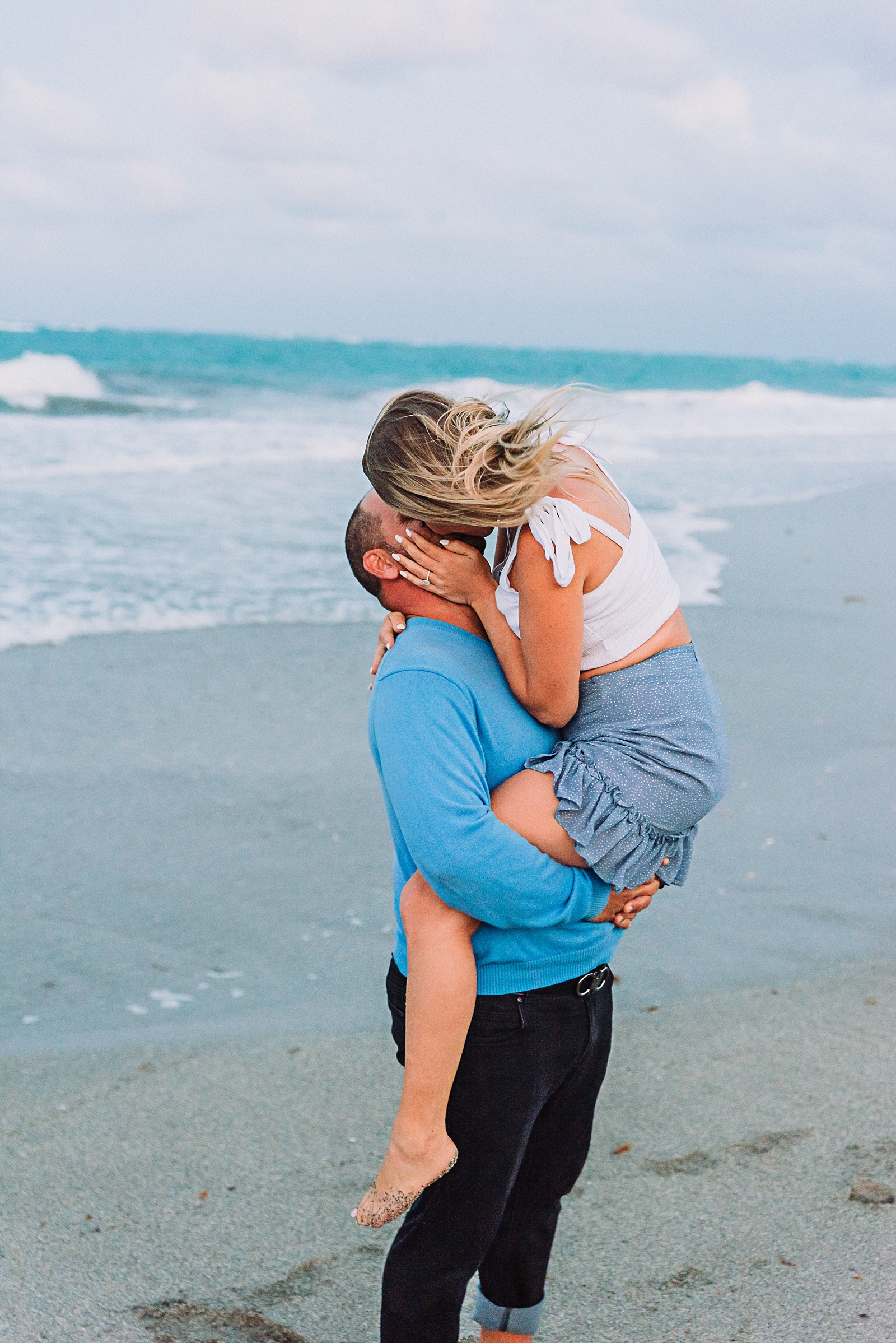 engaged couple kisses on the beach