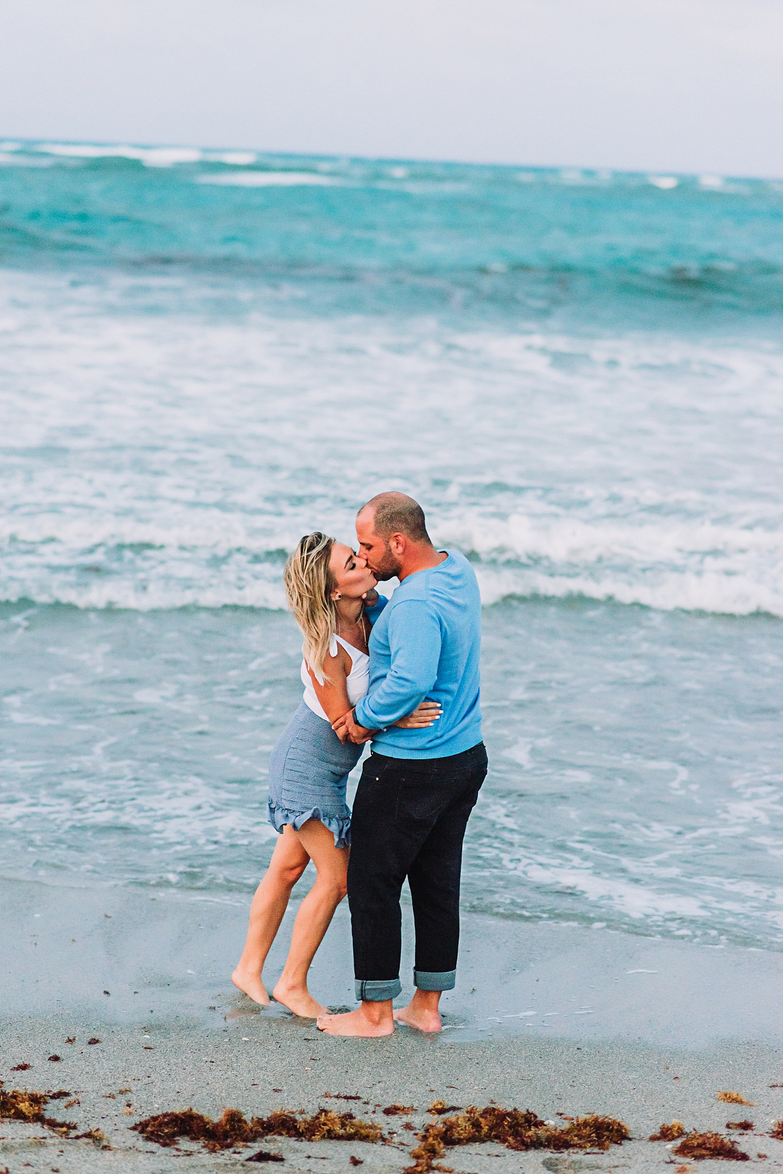 engaged couple kisses on the beach in florida