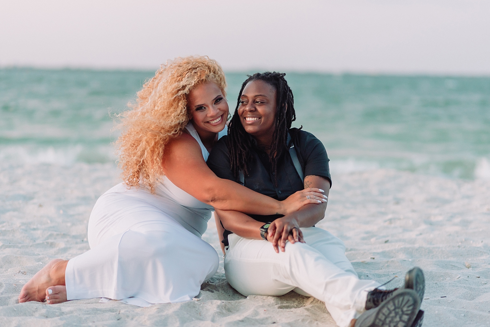 Black Lesbian engagements on Sanibel Island. Same-sex couple celebrates with champagne toasts on the beach in Florida.