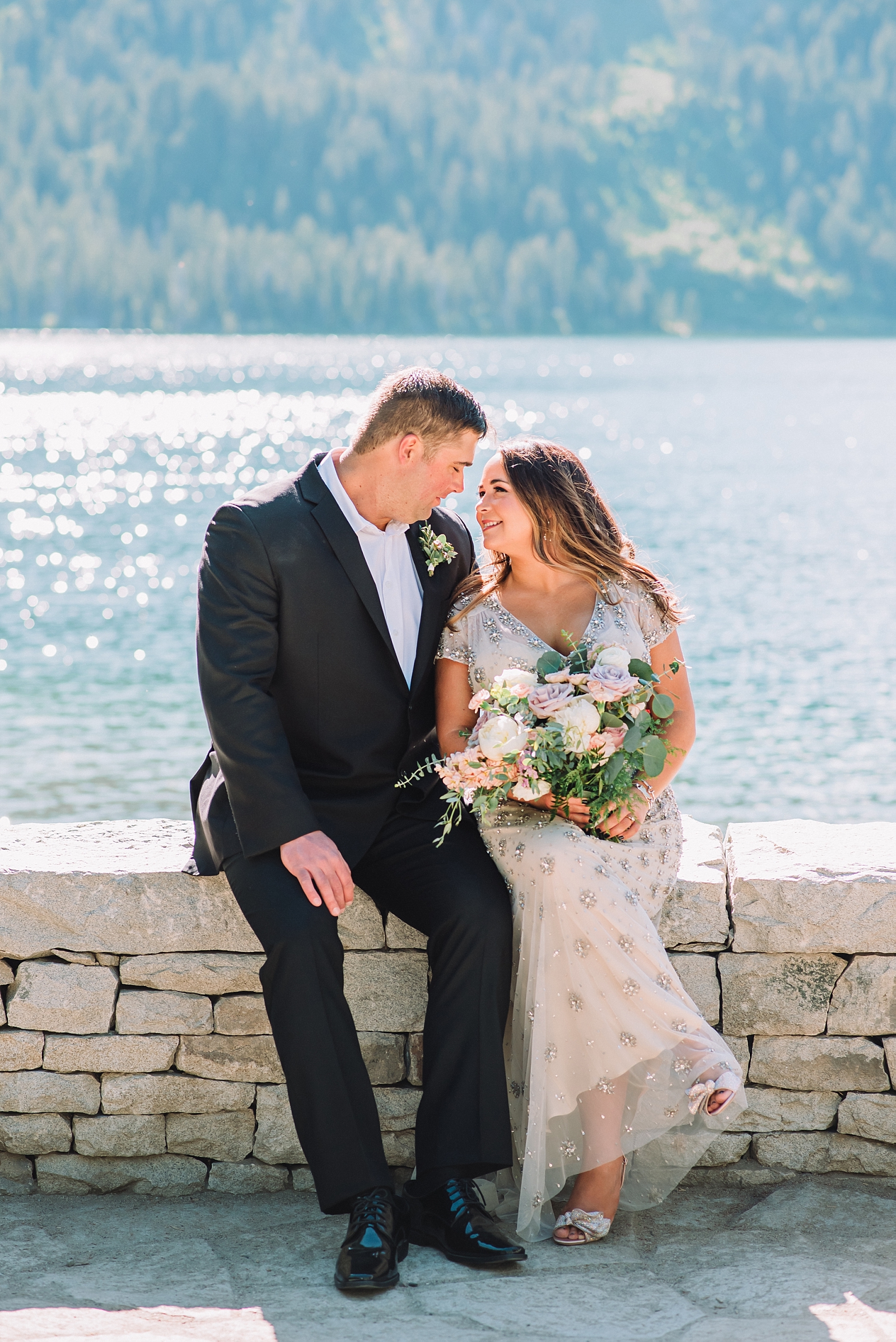 bride and groom sit on stones at Jenny Lake