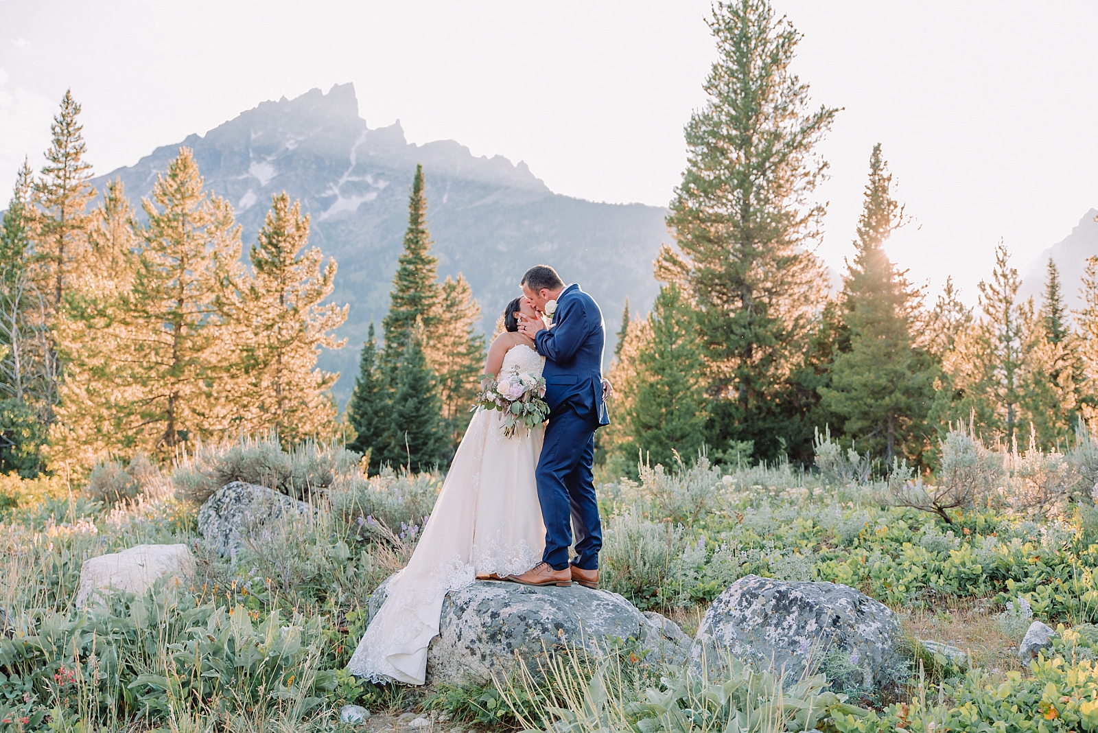 bride and groom kiss under mountains