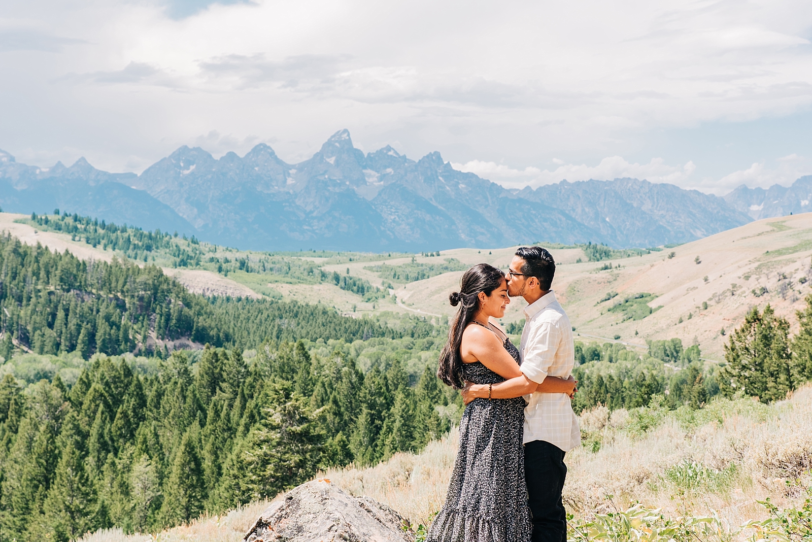 engaged couple kisses in front of the tetons