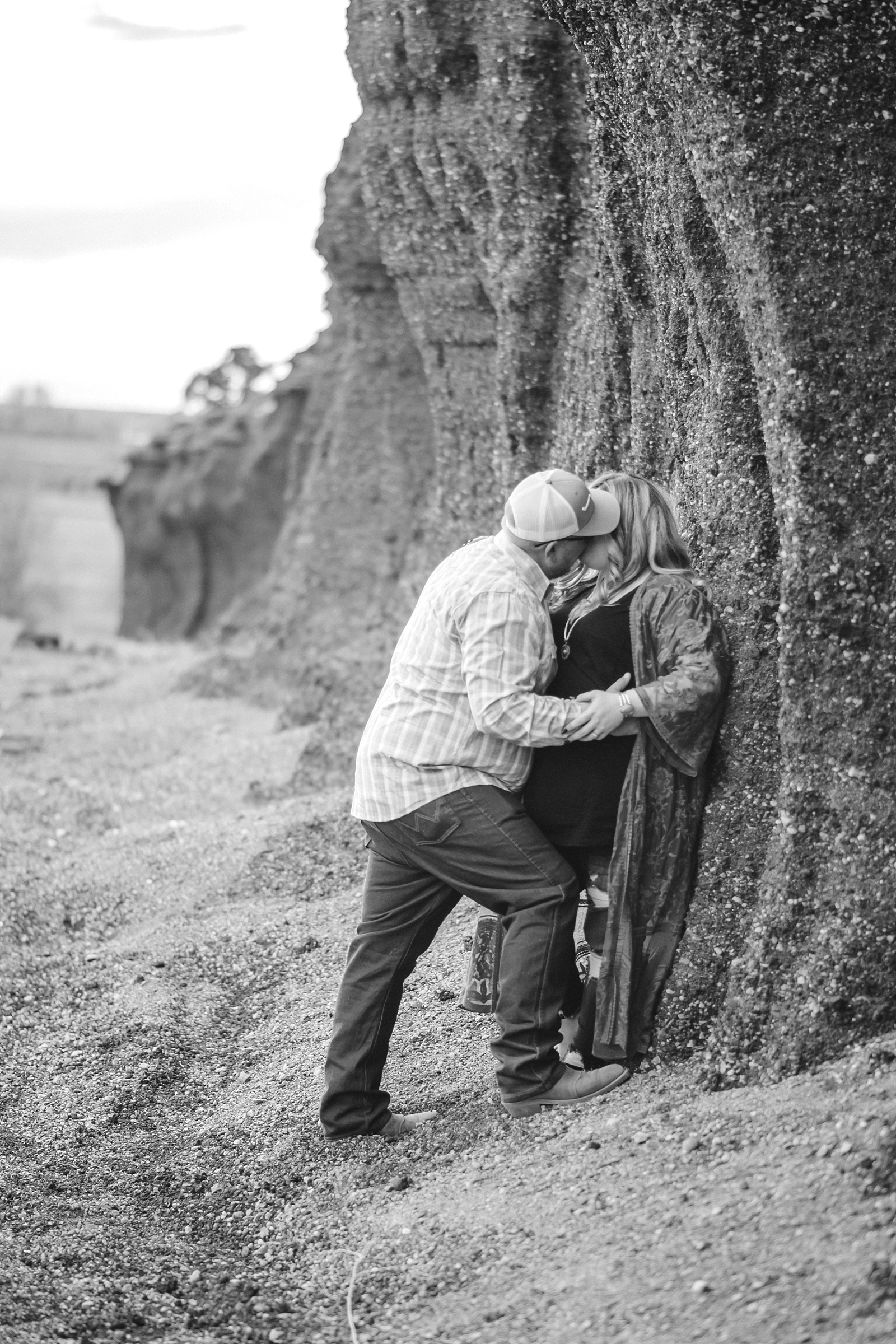 couple kissing against rock wall