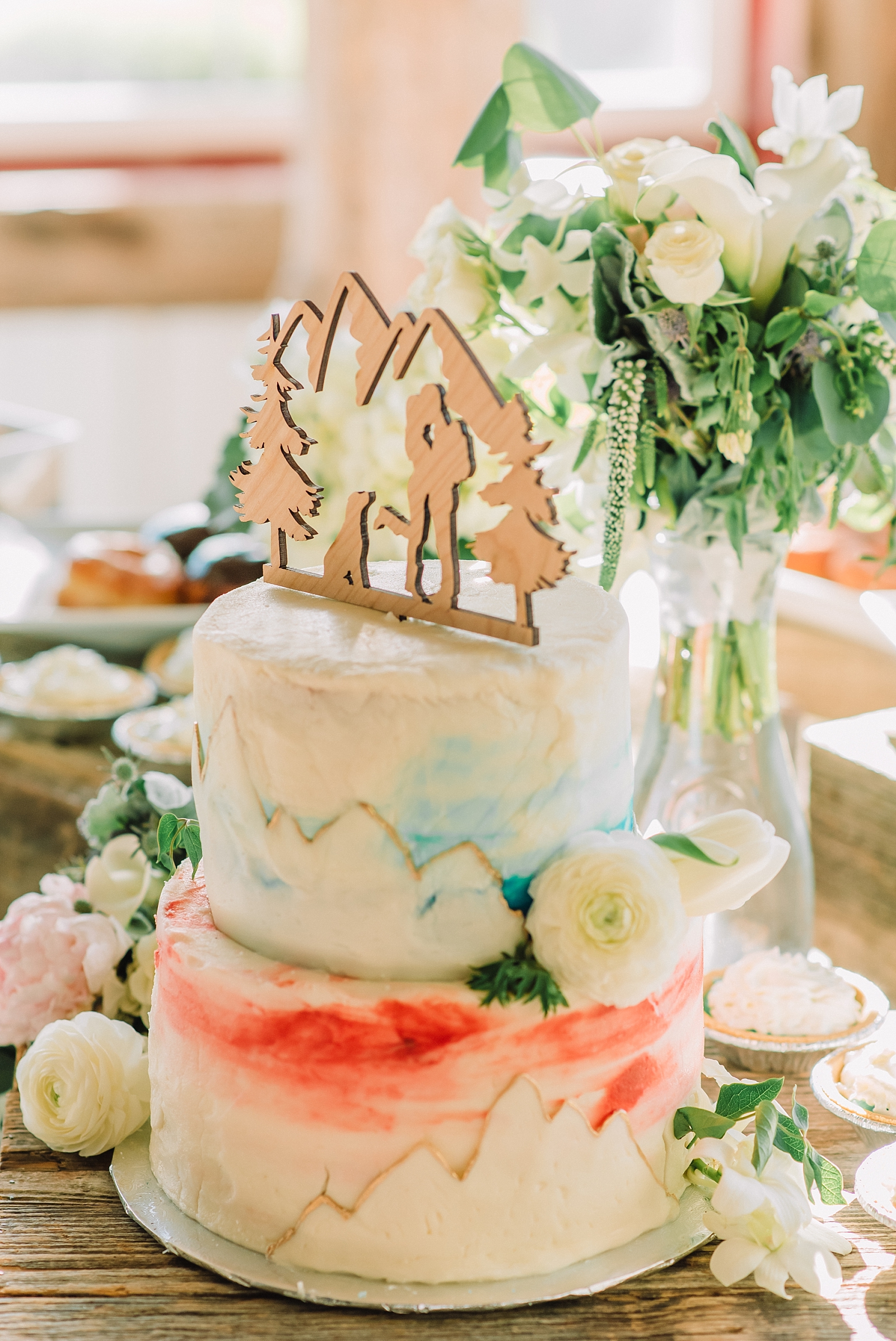 watercolor designed wedding cake with a wood wedding cake topper