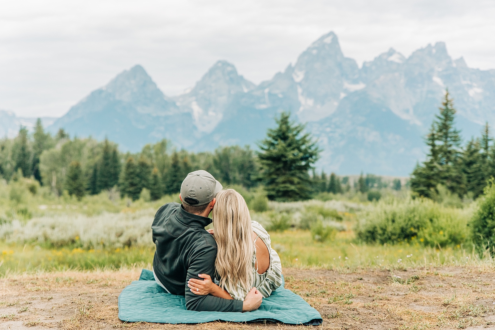 couple snuggles on blanket in the tetons