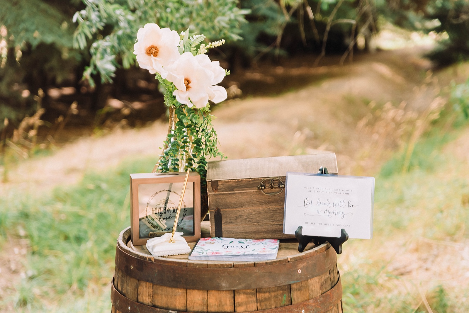 barrel with flowers and sign in book at outdoor wedding