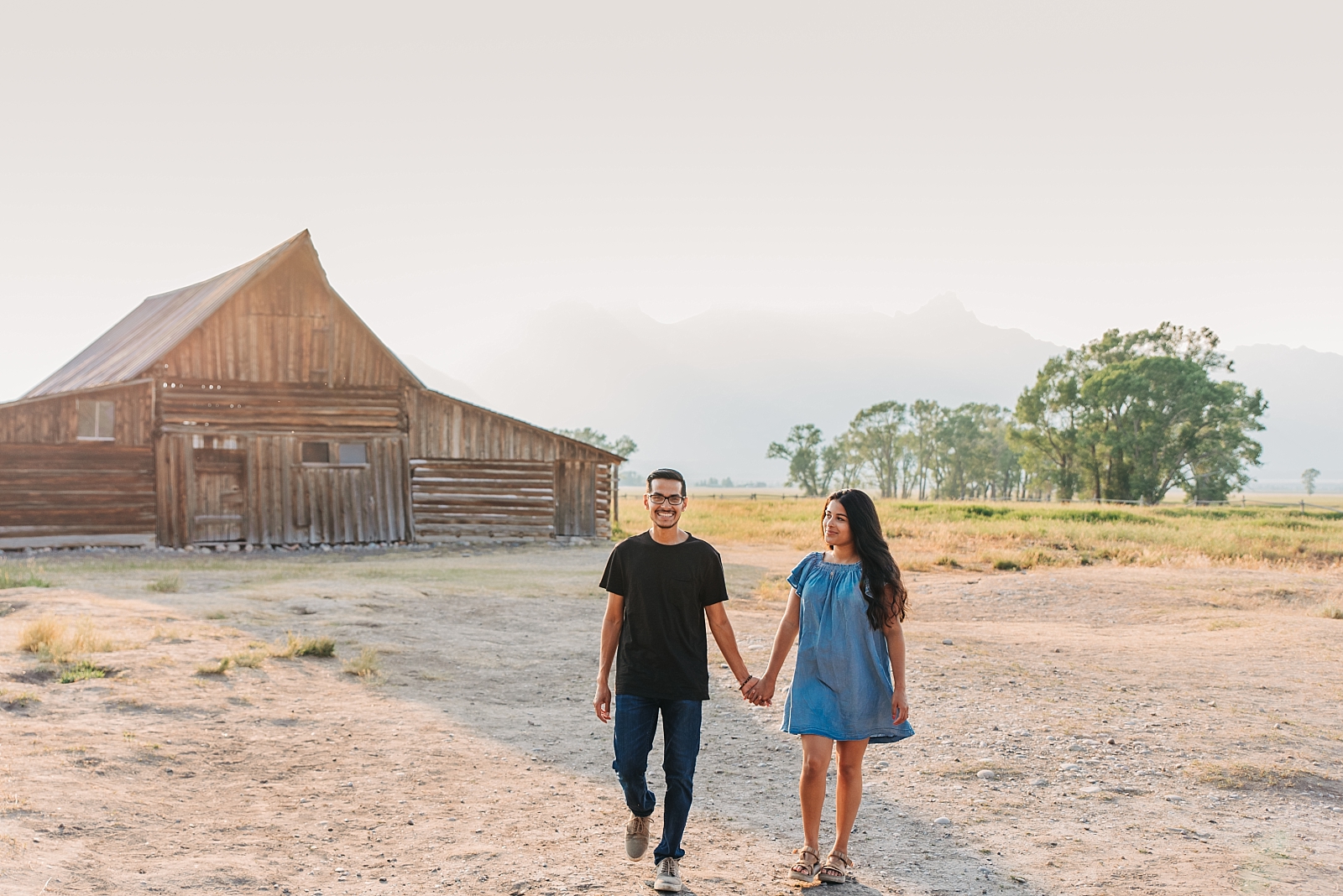 couple walks together in front of barn