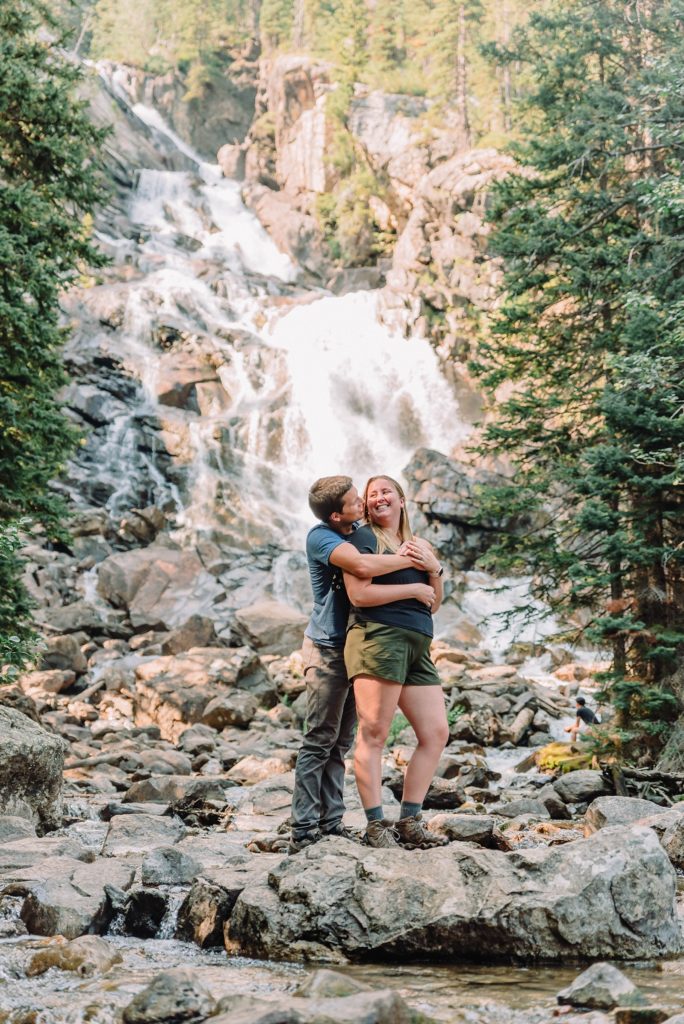 couple kissing in front of water falls