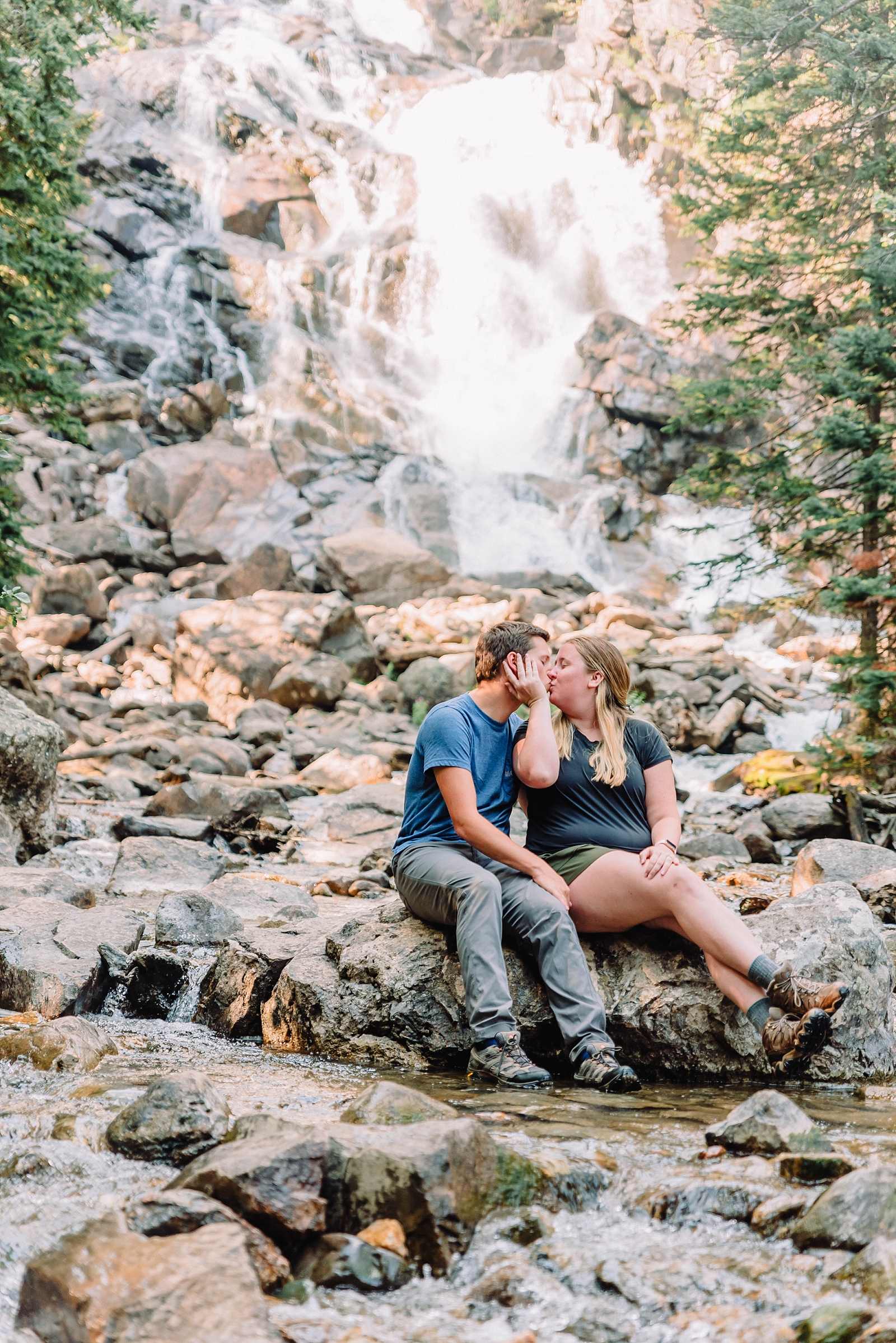 couple kissing in front of water falls