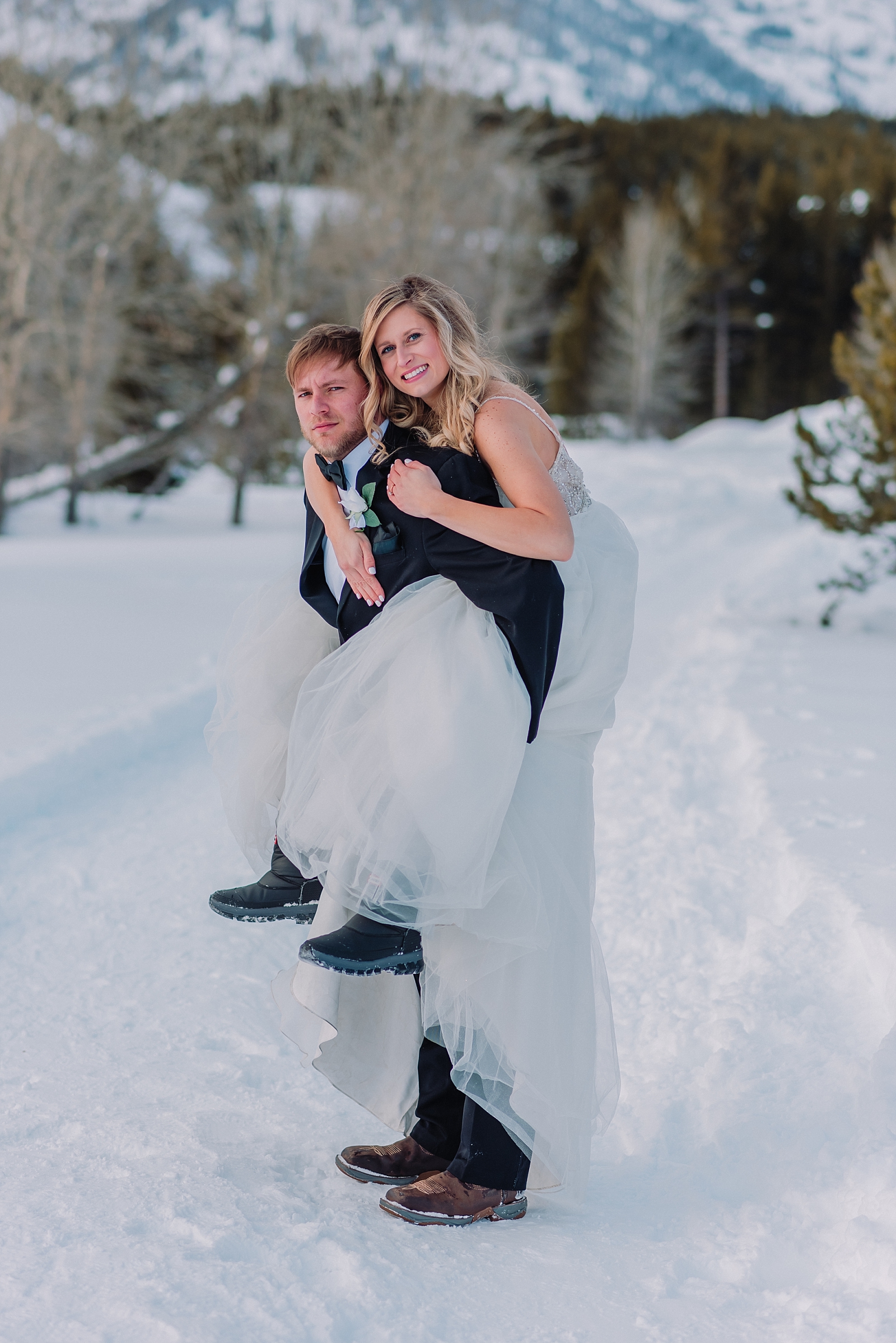 bride and groom walking through snow in snow boots during winter wedding