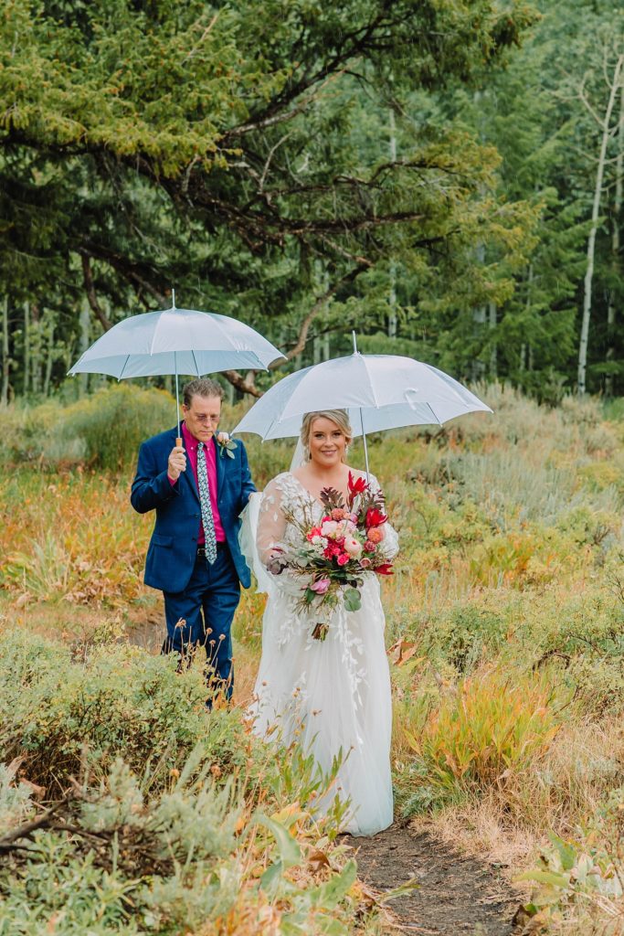 bride under umbrella walking to groom