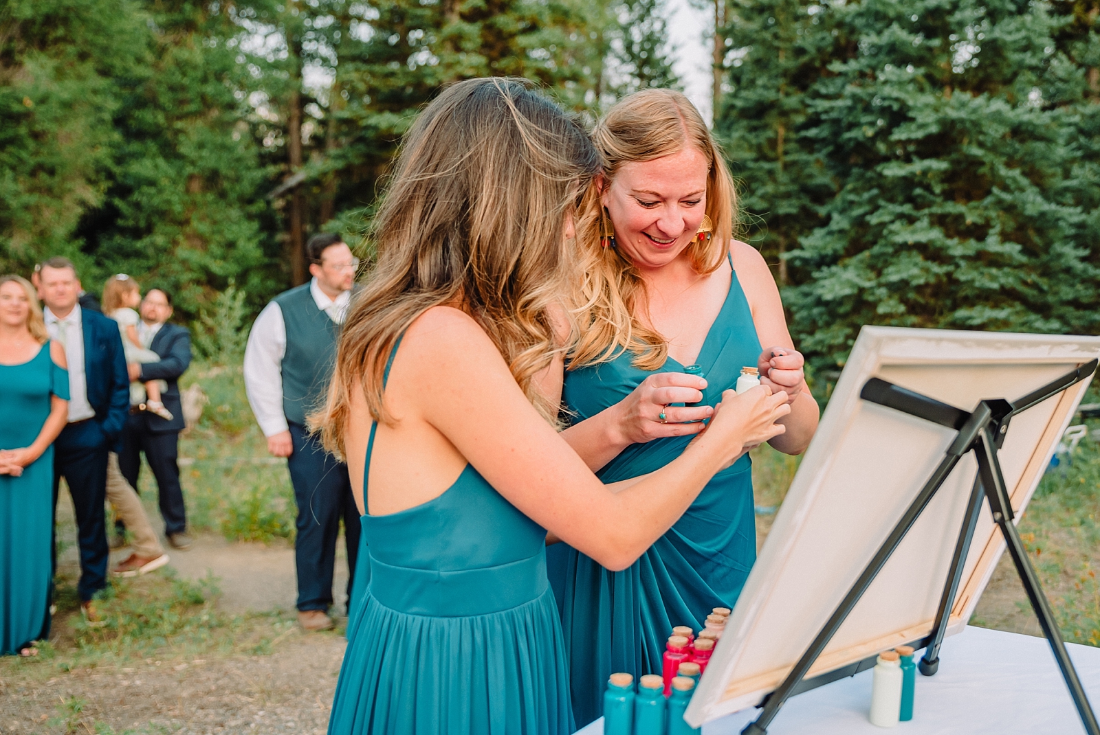 bridesmaids add paint to wedding canvas