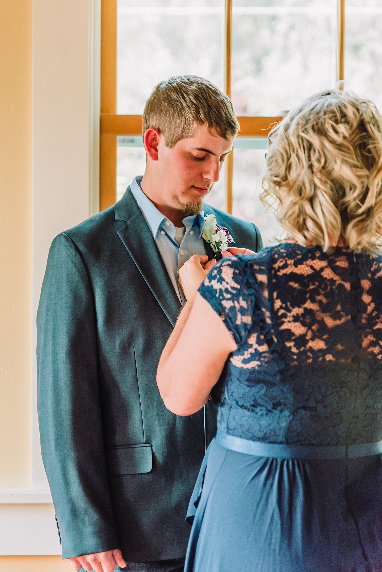 mom pins boutonniere on groom