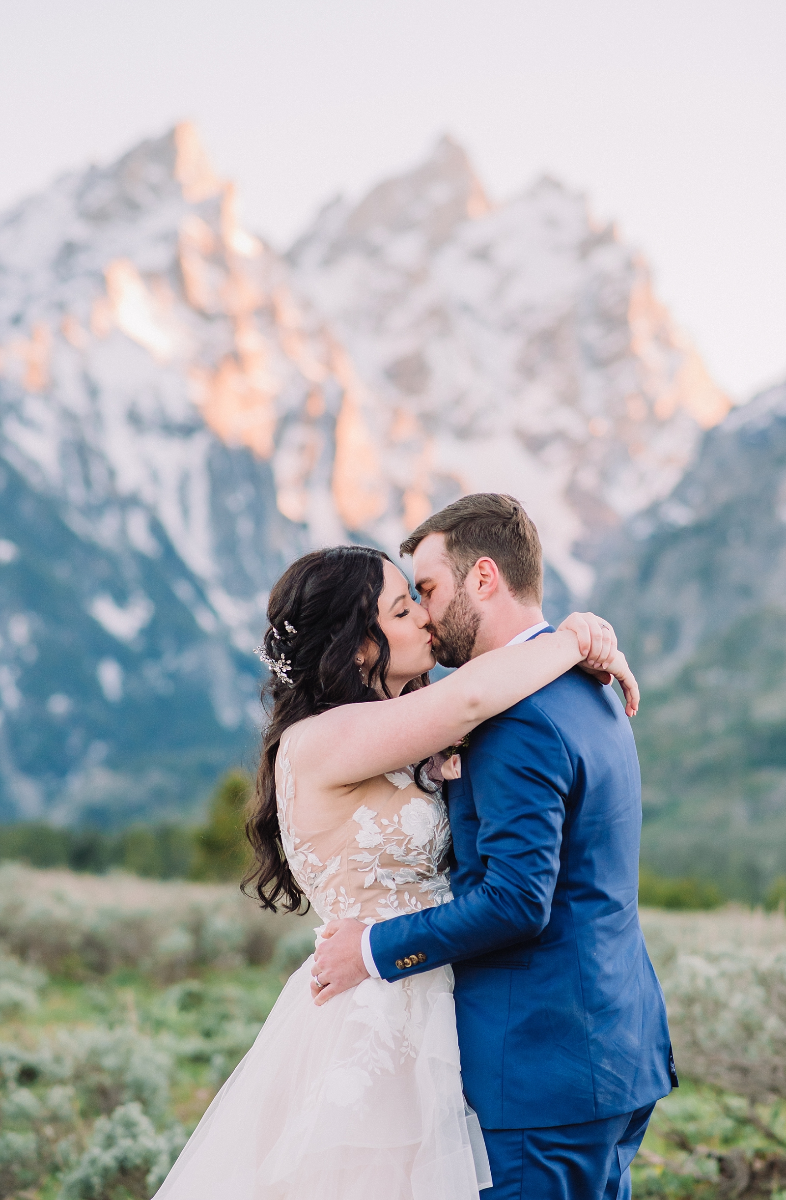Teton wedding day with bride and groom kissing in a meadow in front of the Tetons
