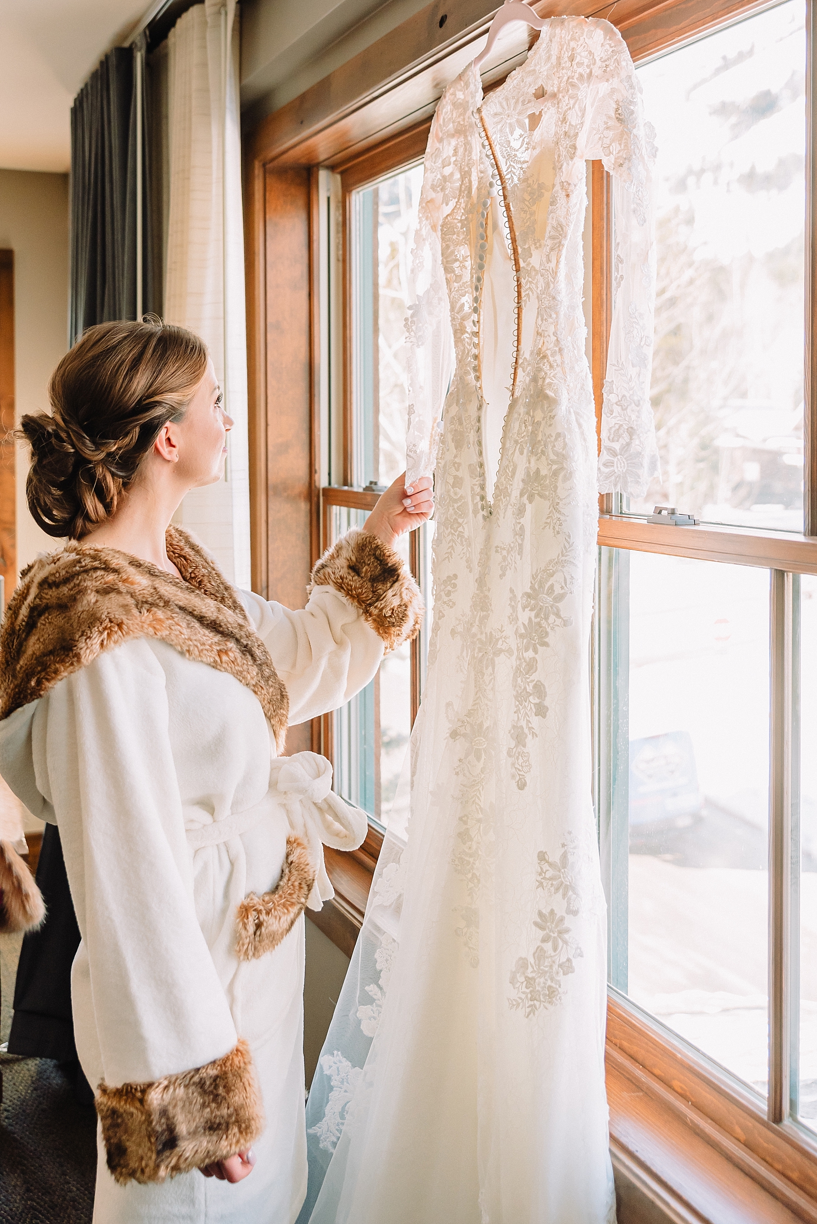 bride in robe looking at wedding dress