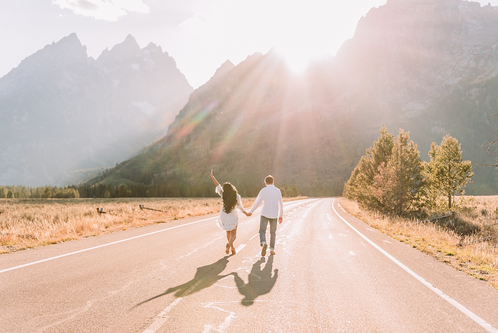 couple walk hand in hand down a road in the mountains