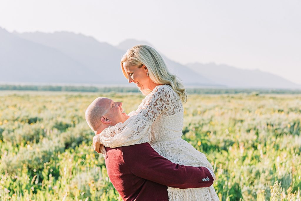 married couple in a field with the teton mountains