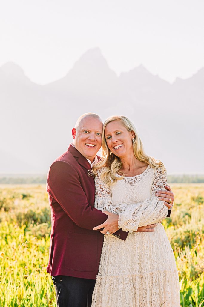 married couple in a field with the teton mountains