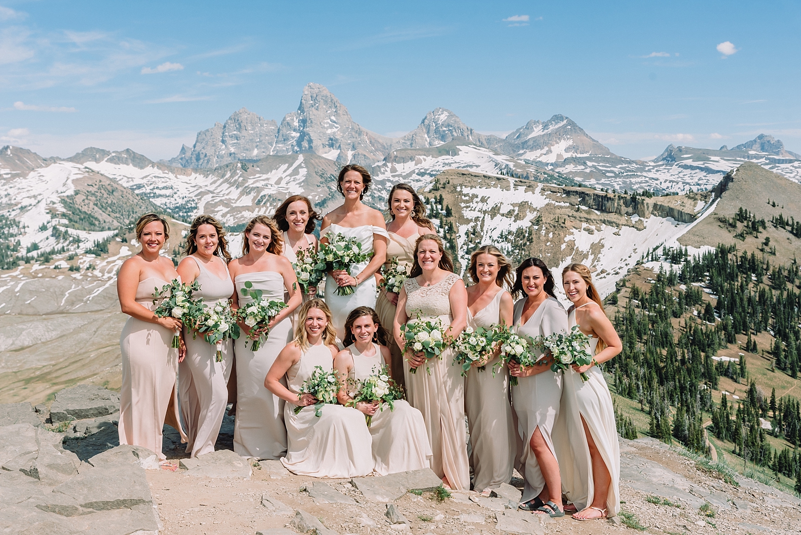 bride with her bridesmaids at the top of targhee resort with the tetons in the background