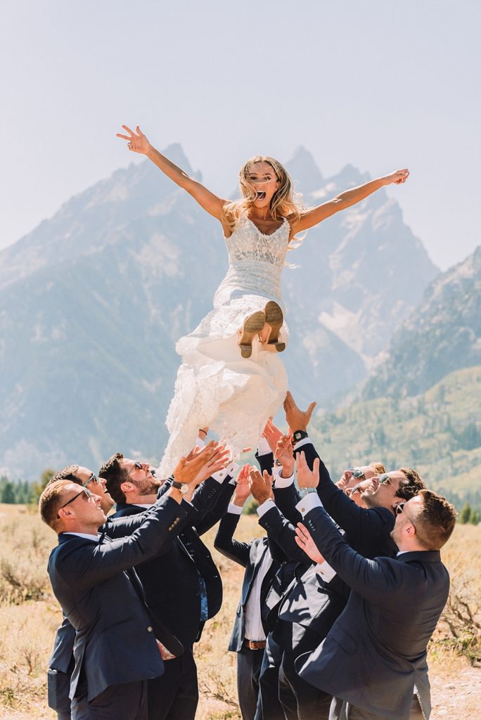 groomsmen throw bride up in the air on wedding day