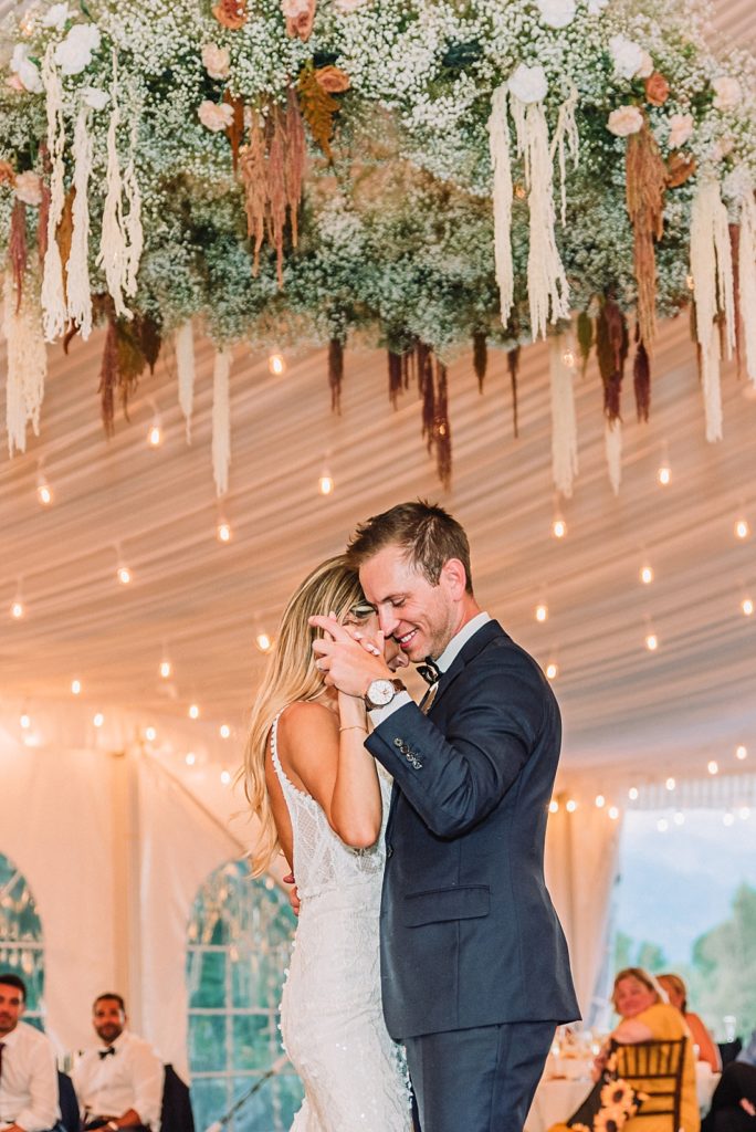 Wedding couple dances under boho floral chandelier