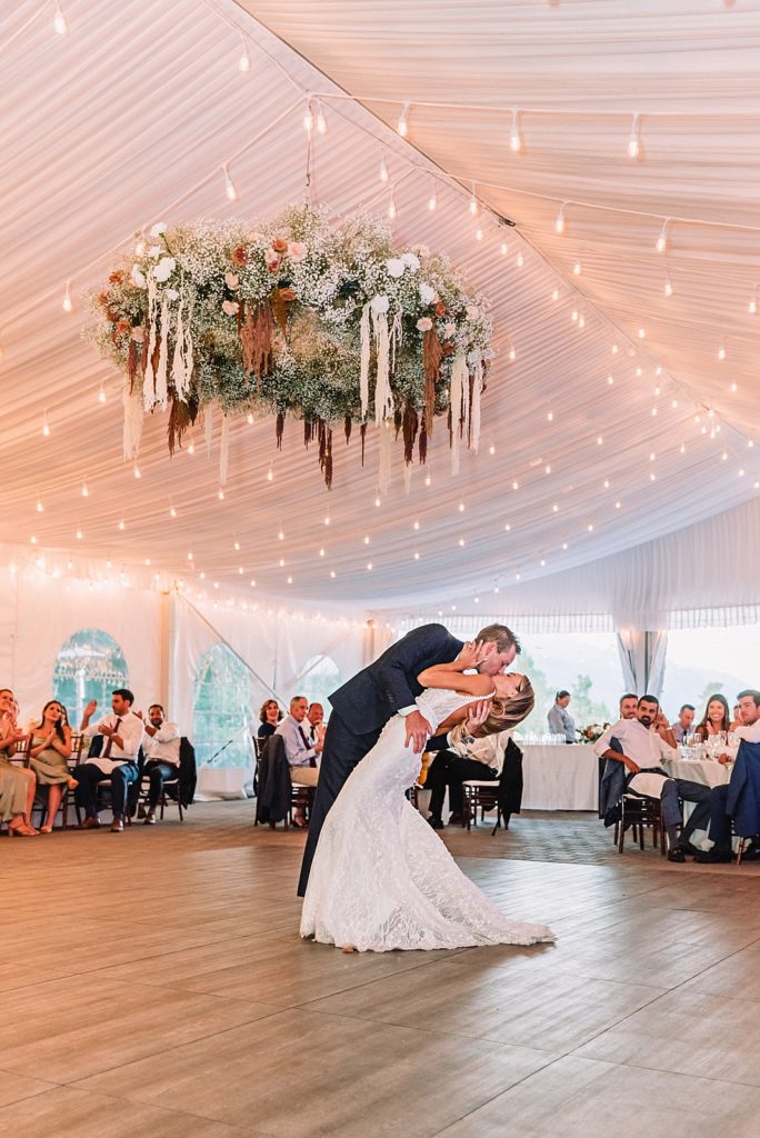 Wedding couple dances under boho floral chandelier, jackson hole golf & tennis club wedding