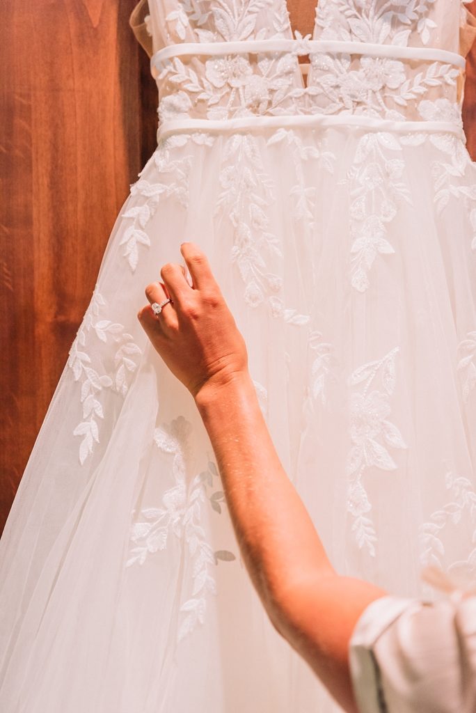 Bride admires her wedding dress as it hangs on the closet doors