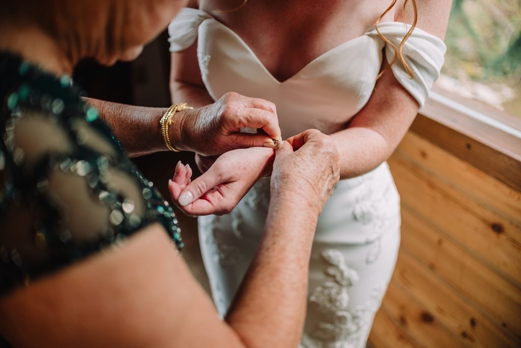 grandmother helps bride put on accessories on wedding day