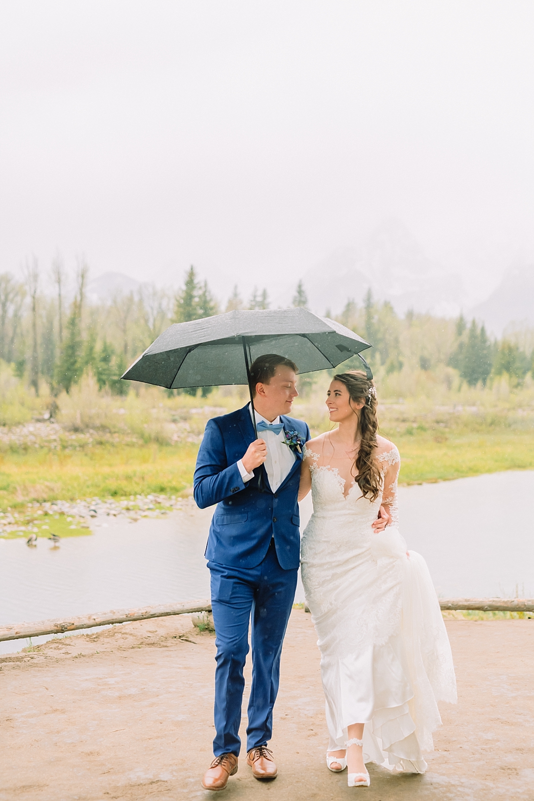 bride and groom walk under umbrella in rainy schwabacher's landing wedding