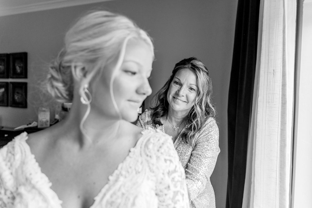 mother helps daughter get ready on the wedding day